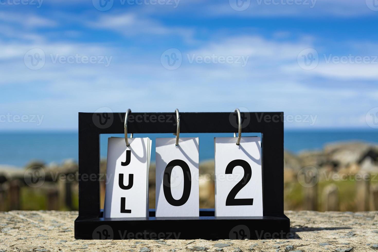 juil 02 texte de la date du calendrier sur cadre en bois avec arrière-plan flou de l'océan. photo