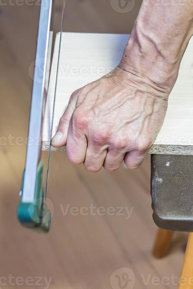 homme sciant une planche avec une scie à métaux photo