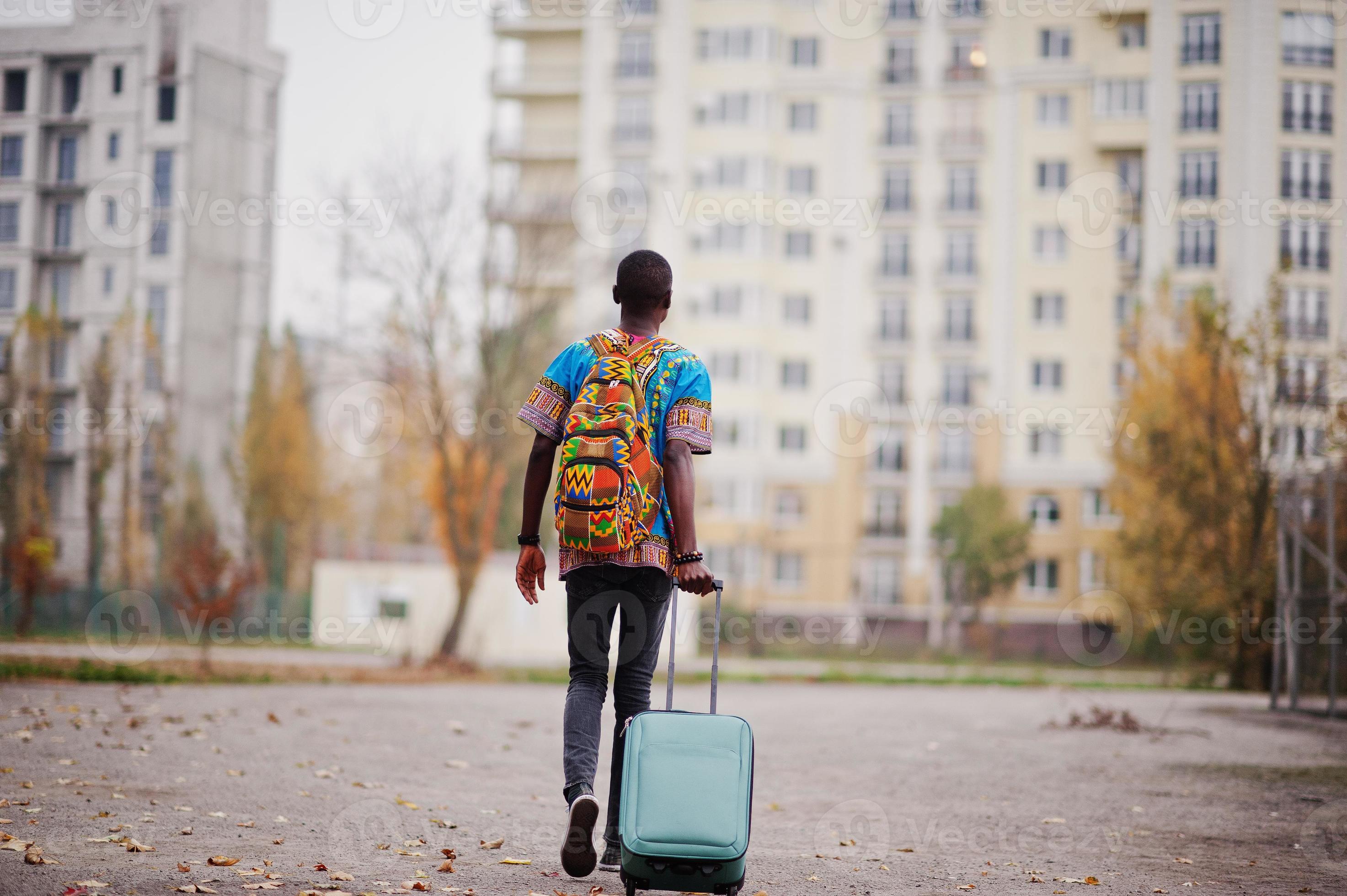 homme afro-américain en chemise à carreaux, avec valise et sac à dos.  voyageur d'homme noir au parc d'automne parlant au téléphone portable.  10570233 Photo de stock chez Vecteezy