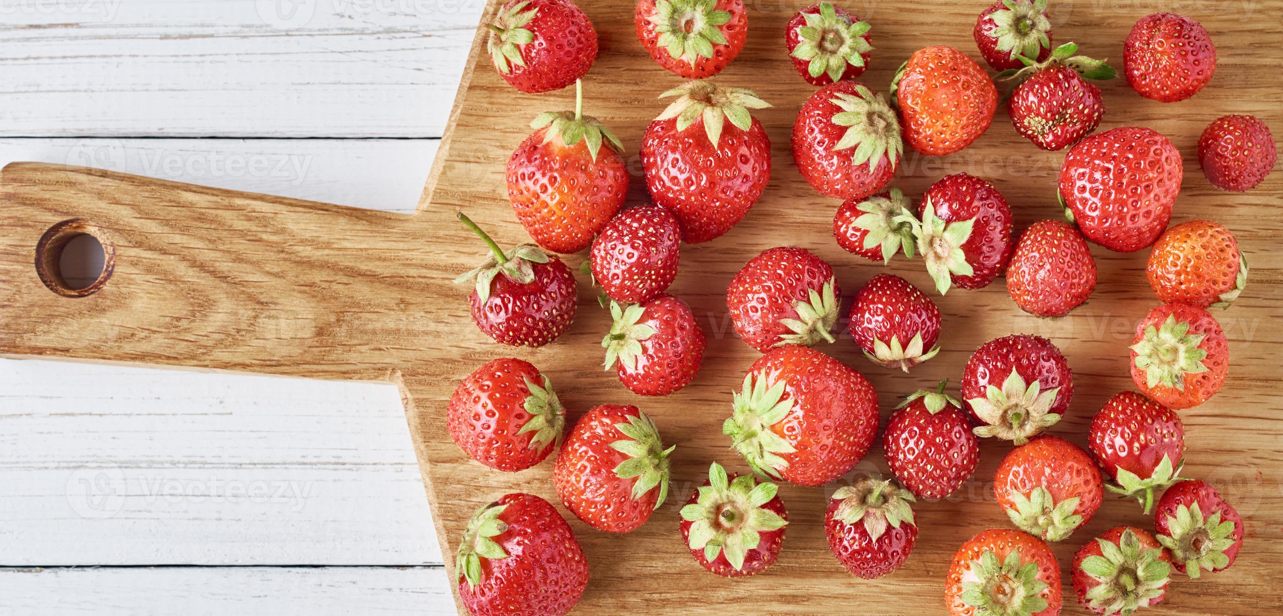 tas de fraises fraîches avec planche à découper sur fond gris, vue