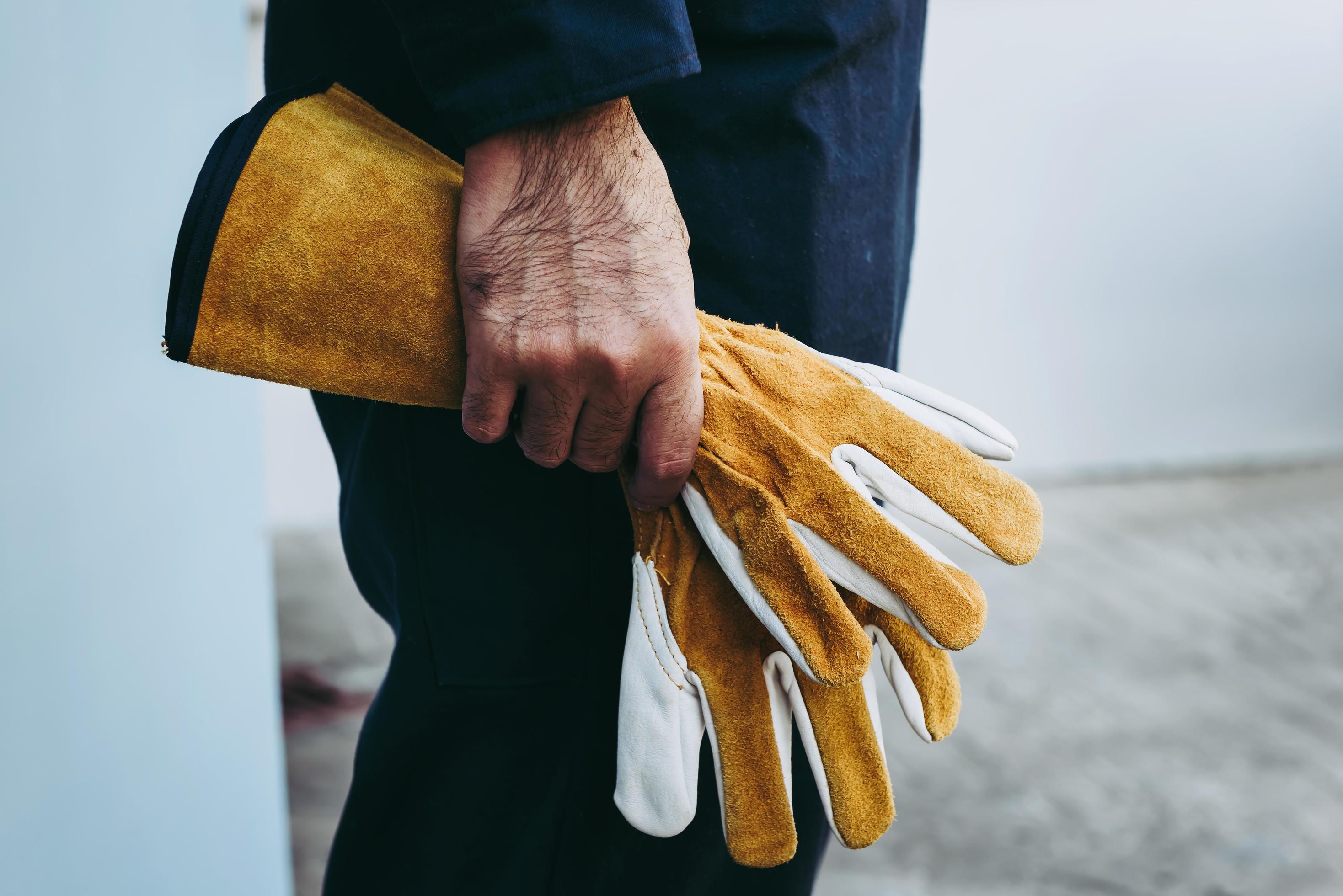 Gros plan de l'homme tenant des gants de travail jaunes 1227893