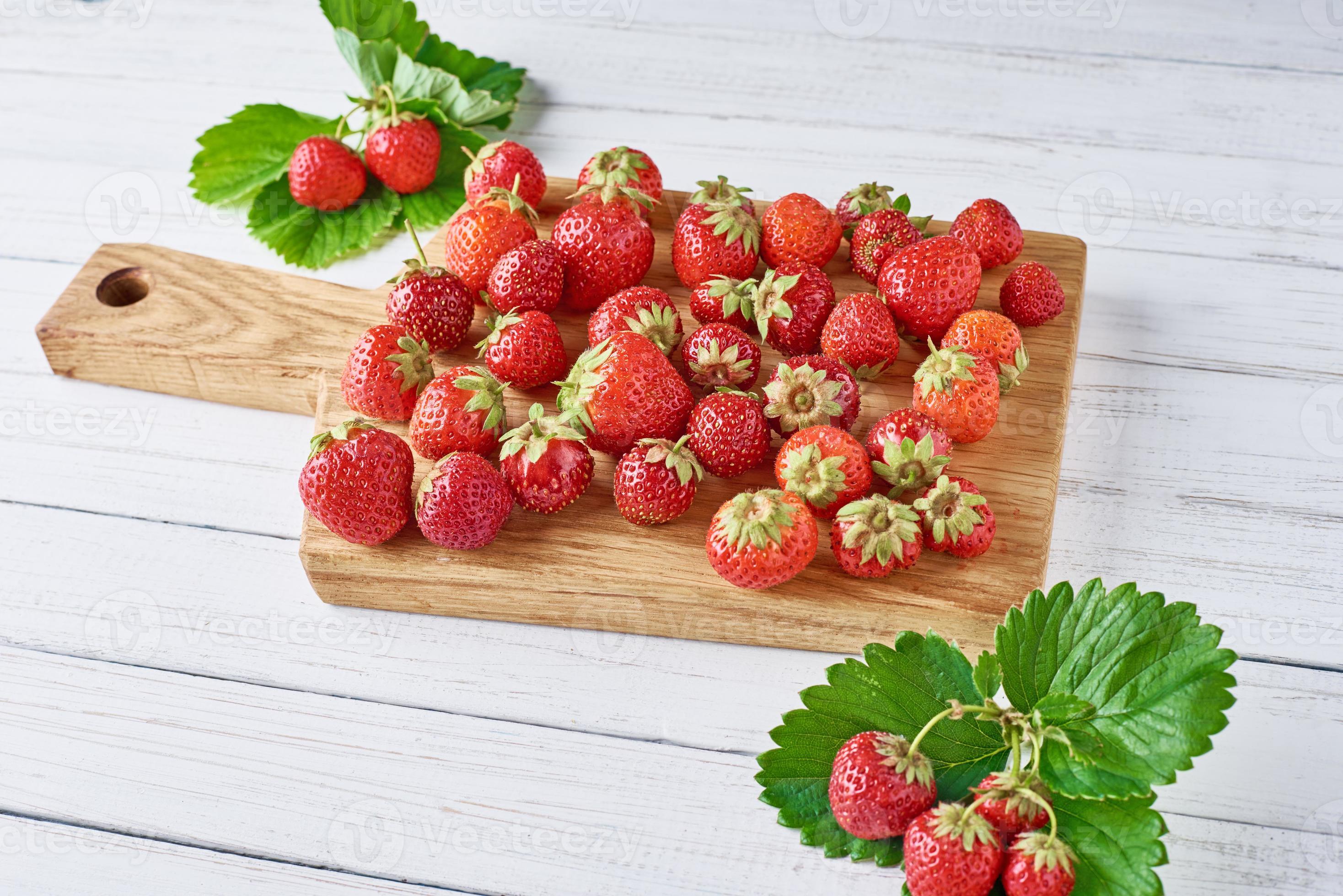 tas de fraises fraîches avec une planche à découper sur un fond en