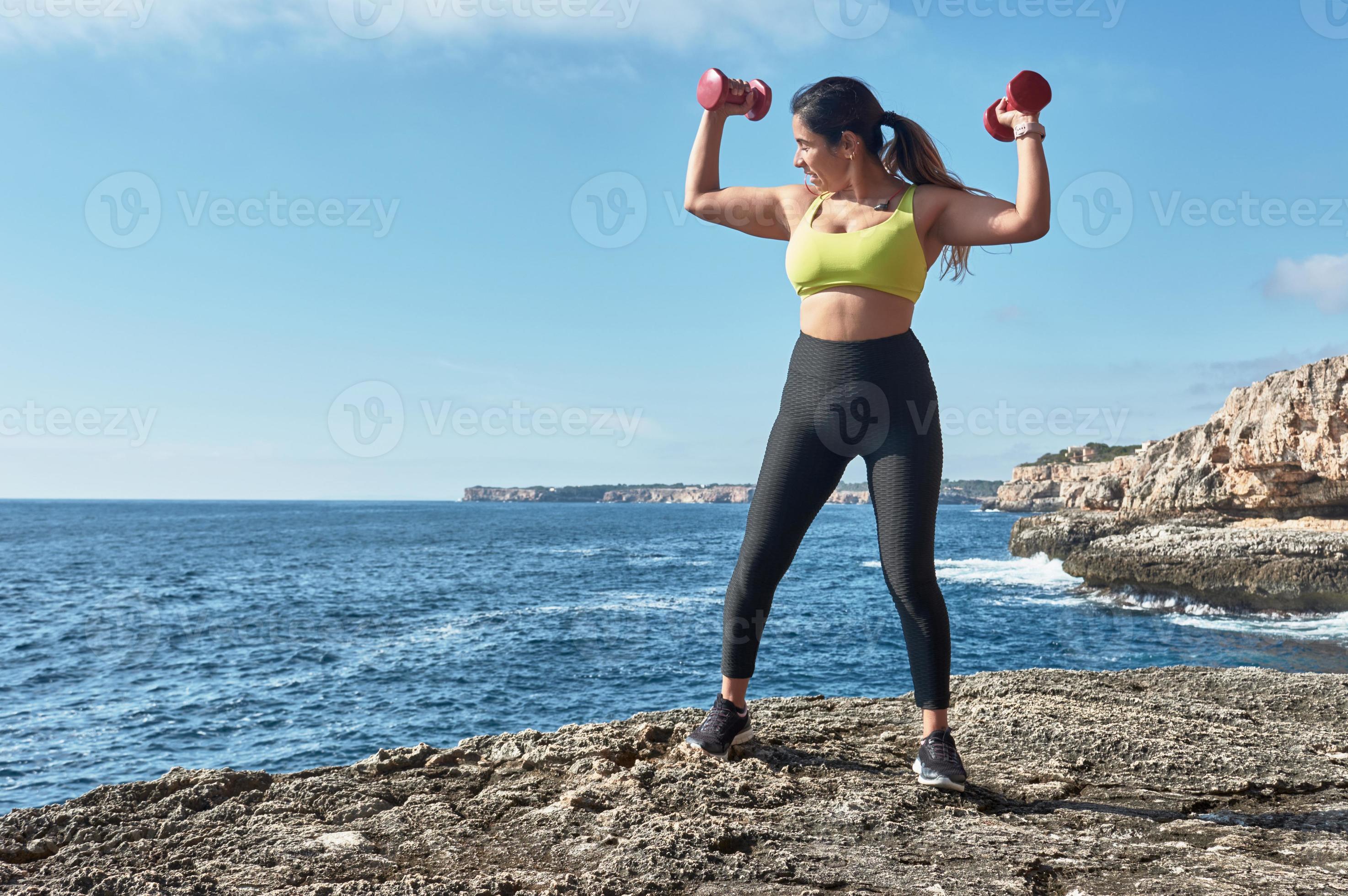 fitness femme latine dans l'ensemble sportif entraînement avec bande  élastique, poids, exercices de gym, devant l'eau. 14005390 Photo de stock  chez Vecteezy