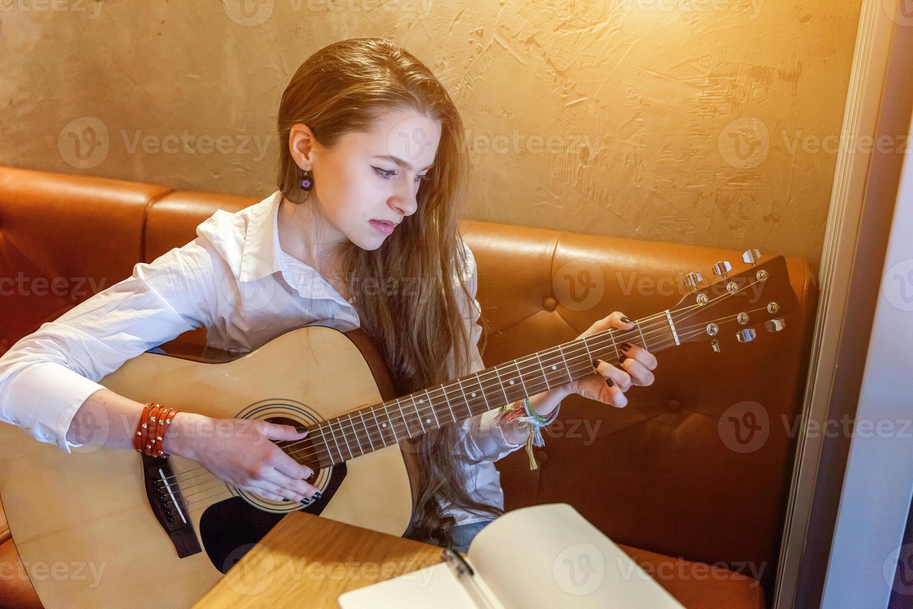 jeune fille jouant de la guitare au café 14949257 Photo de stock chez  Vecteezy