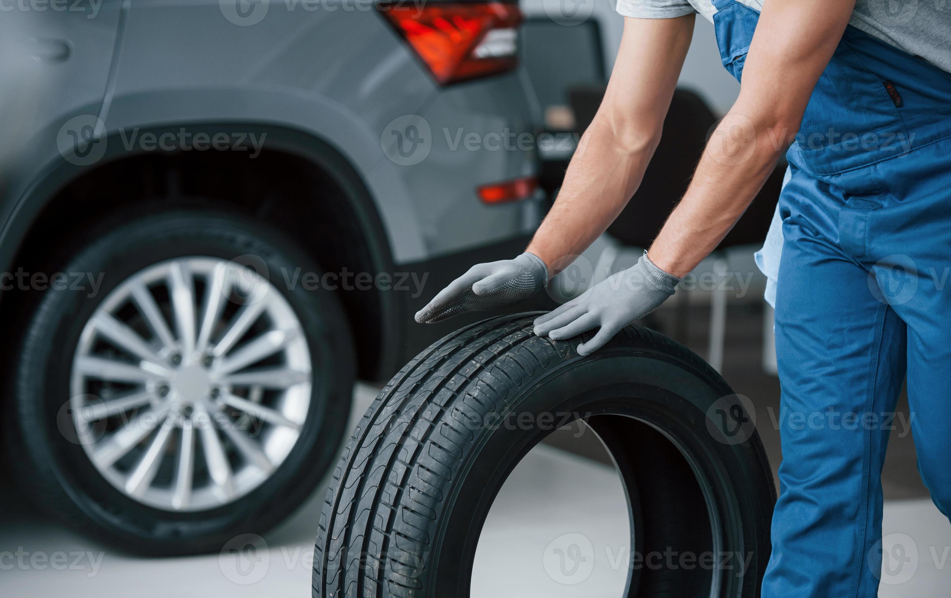 Art Du Transport. Mécanicien Tenant Un Pneu Au Garage De Réparation.  Remplacement Des Pneus D'hiver Et D'été