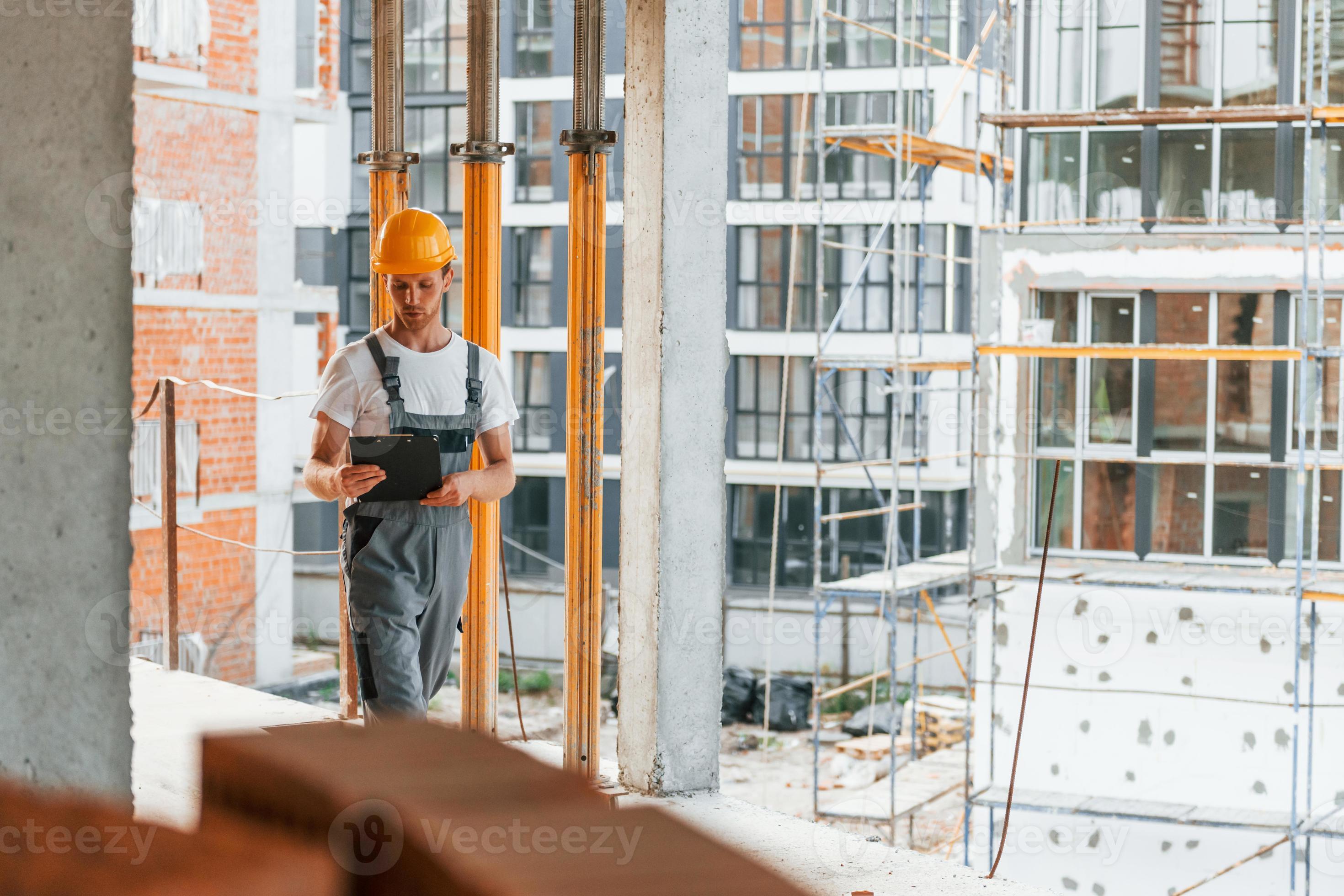 casque de chantier de couleur jaune. jeune homme travaillant en uniforme à  la construction pendant la journée 15458667 Photo de stock chez Vecteezy