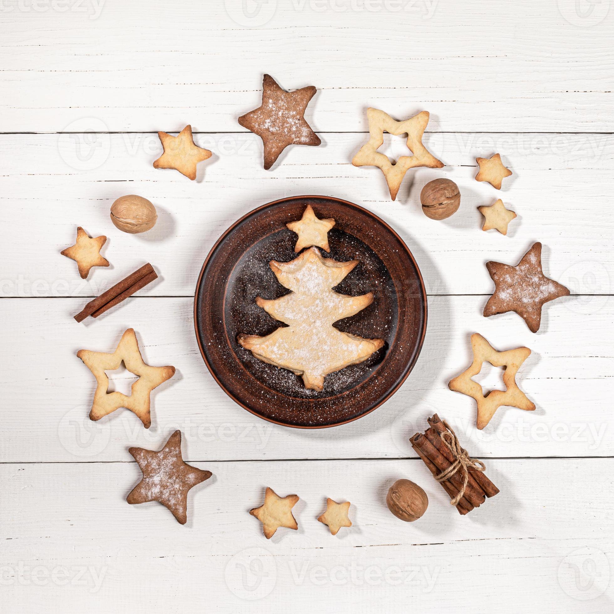 cuisson comme arbre de noël sur une plaque brune, biscuits en forme d'étoile,  noix, cannelle sur une table en bois blanche. 15473435 Photo de stock chez  Vecteezy