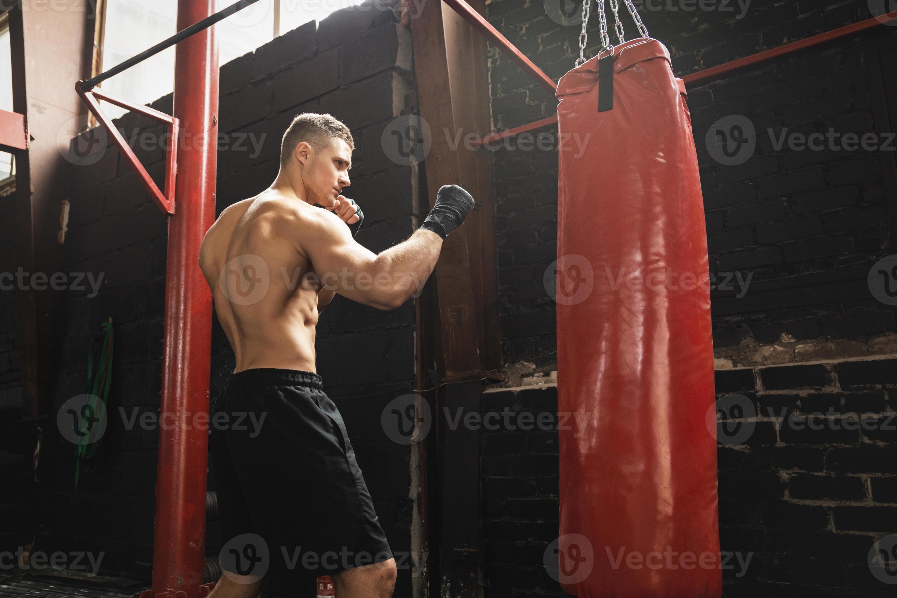 Poing D'un Homme Avec Un Gant De Boxe Rouge Frappant Un Sac De Boxe Noir  Sur Un Mur Noir