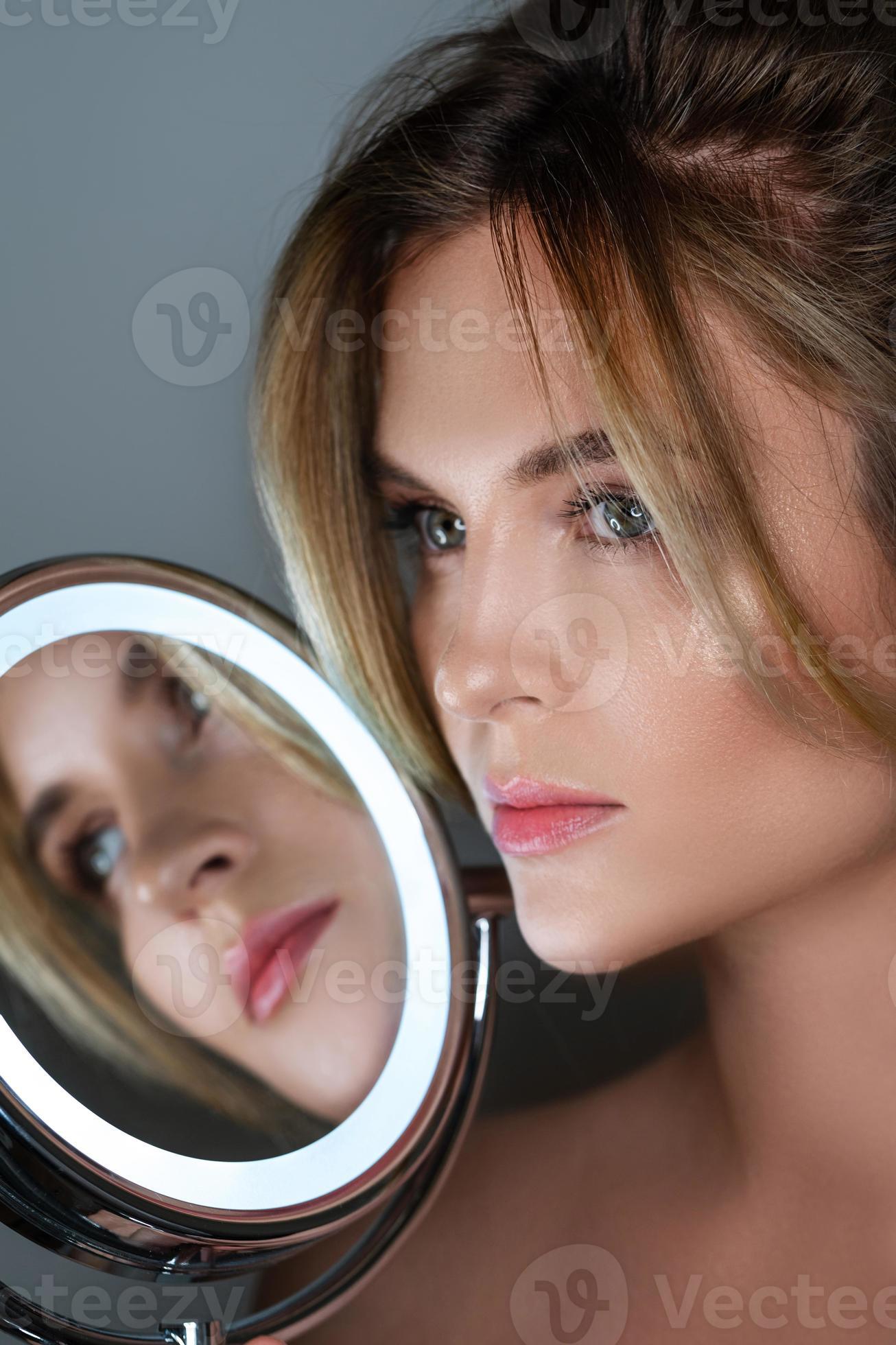 belle femme avec pinceau de maquillage et miroir rond avec lumière led  16251014 Photo de stock chez Vecteezy