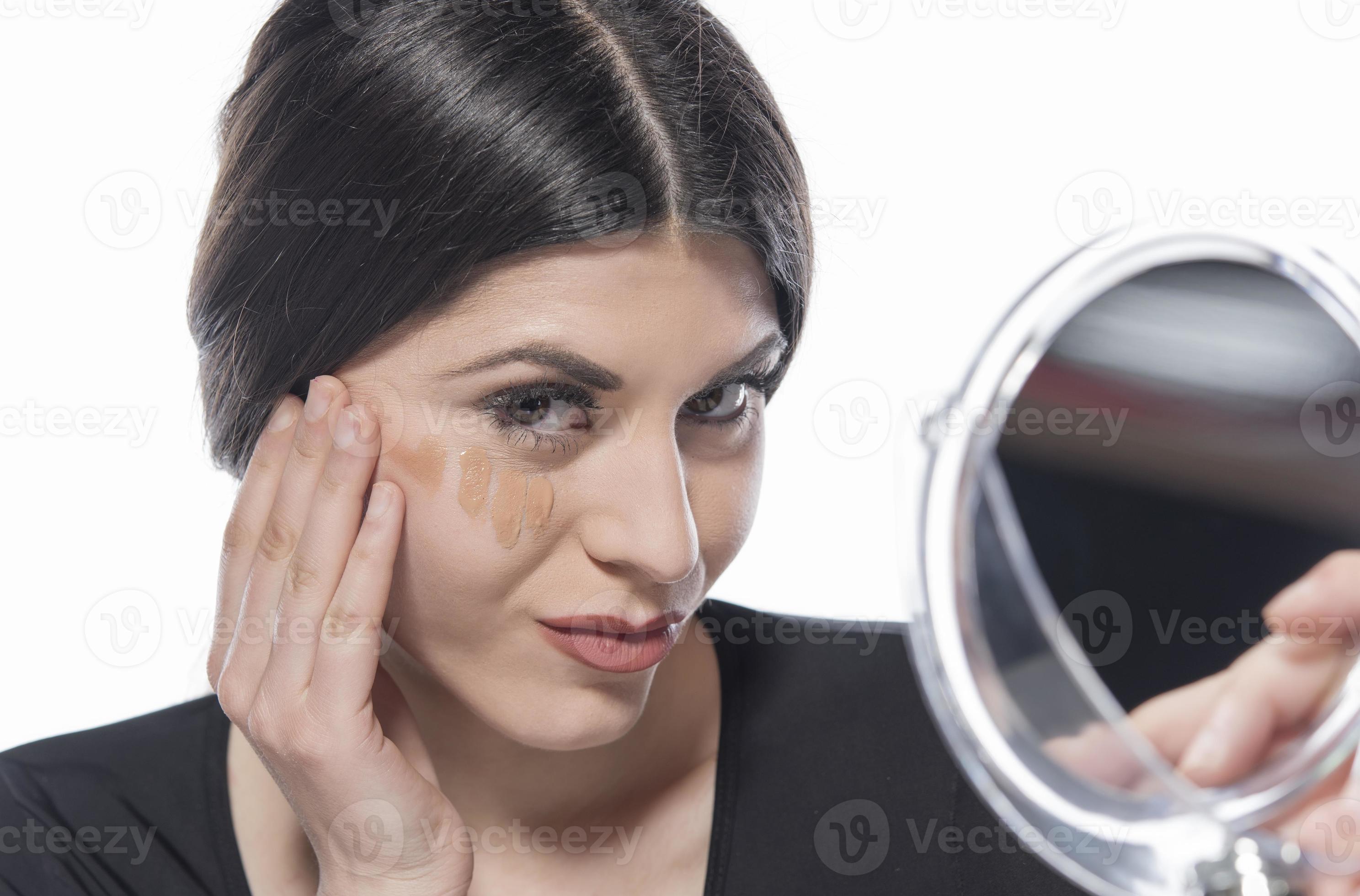 portrait d'une jeune femme appliquant un maquillage liquide sur son visage.  isolé sur fond blanc 16606369 Photo de stock chez Vecteezy