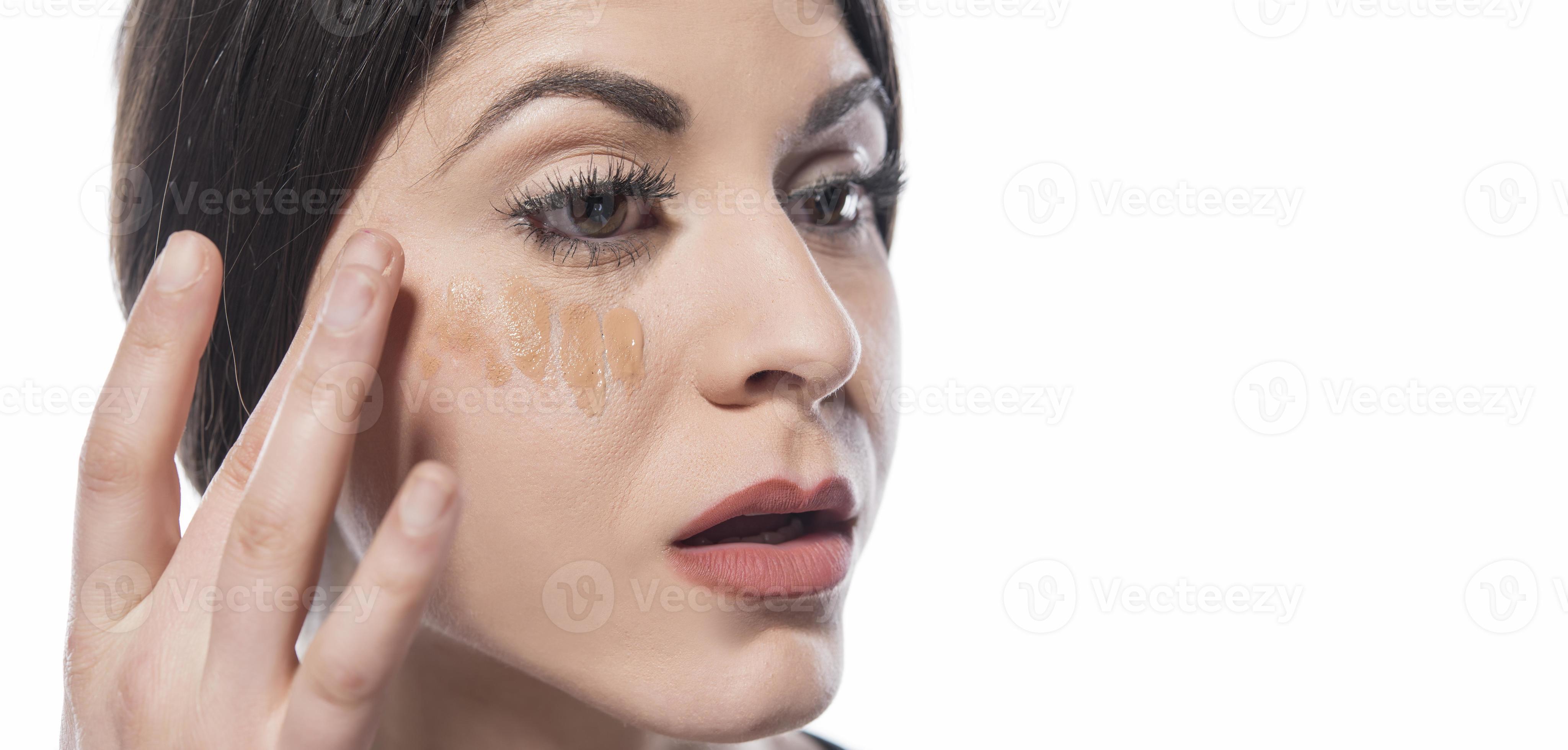 portrait d'une jeune femme appliquant un maquillage liquide sur son visage.  isolé sur fond blanc 16606369 Photo de stock chez Vecteezy