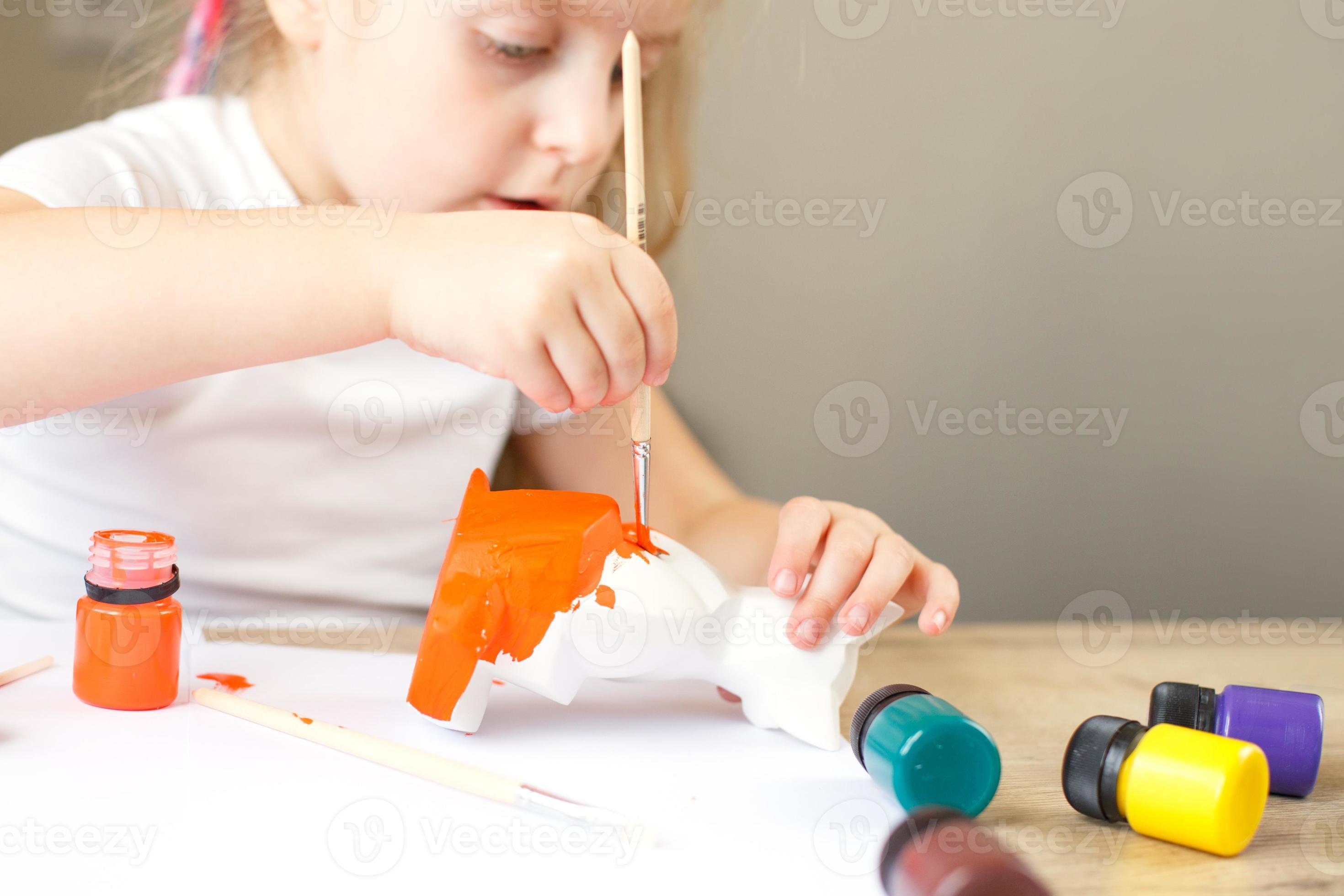 une petite fille peint un renard jouet en argile. notion de