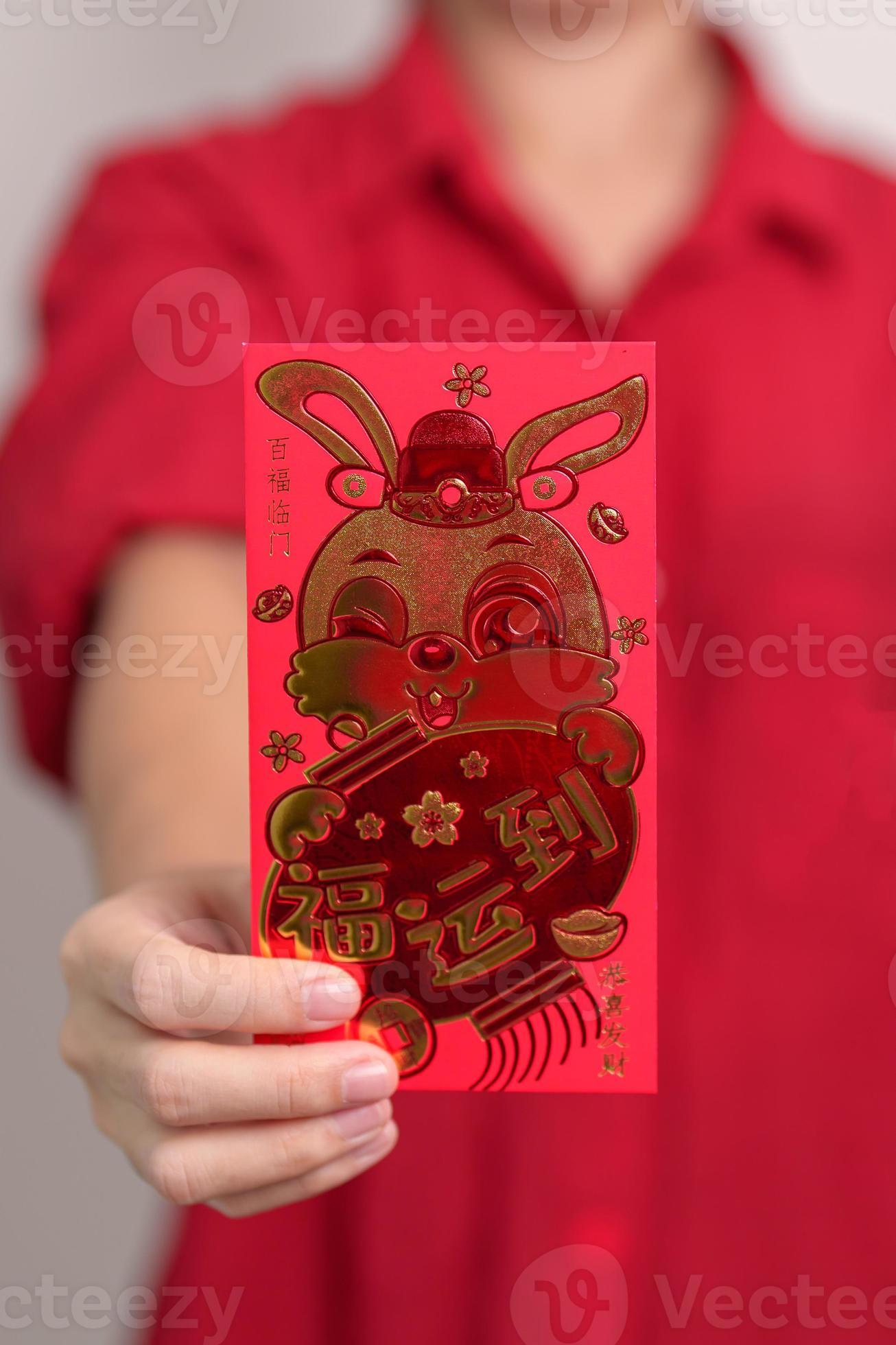 femme tenant une enveloppe rouge chinoise avec lapin doré et mot de  bénédiction, cadeau en argent pour les vacances du nouvel an lunaire.  phrase chinoise signifie bonheur, en bonne santé, chanceux et