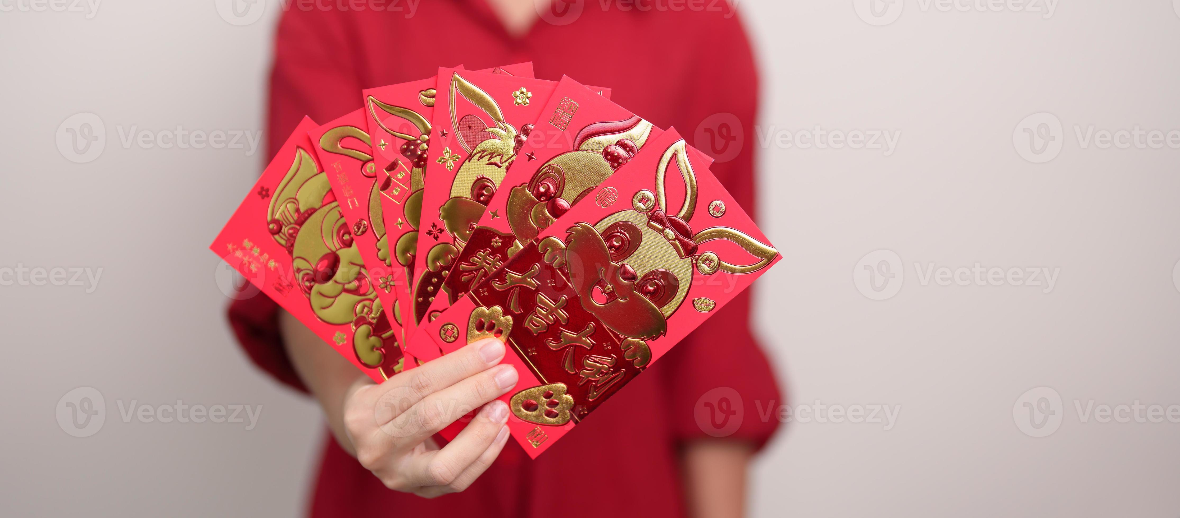 femme tenant une enveloppe rouge chinoise avec lapin doré et mot de  bénédiction, cadeau en argent pour les vacances du nouvel an lunaire.  phrase chinoise signifie bonheur, en bonne santé, chanceux et