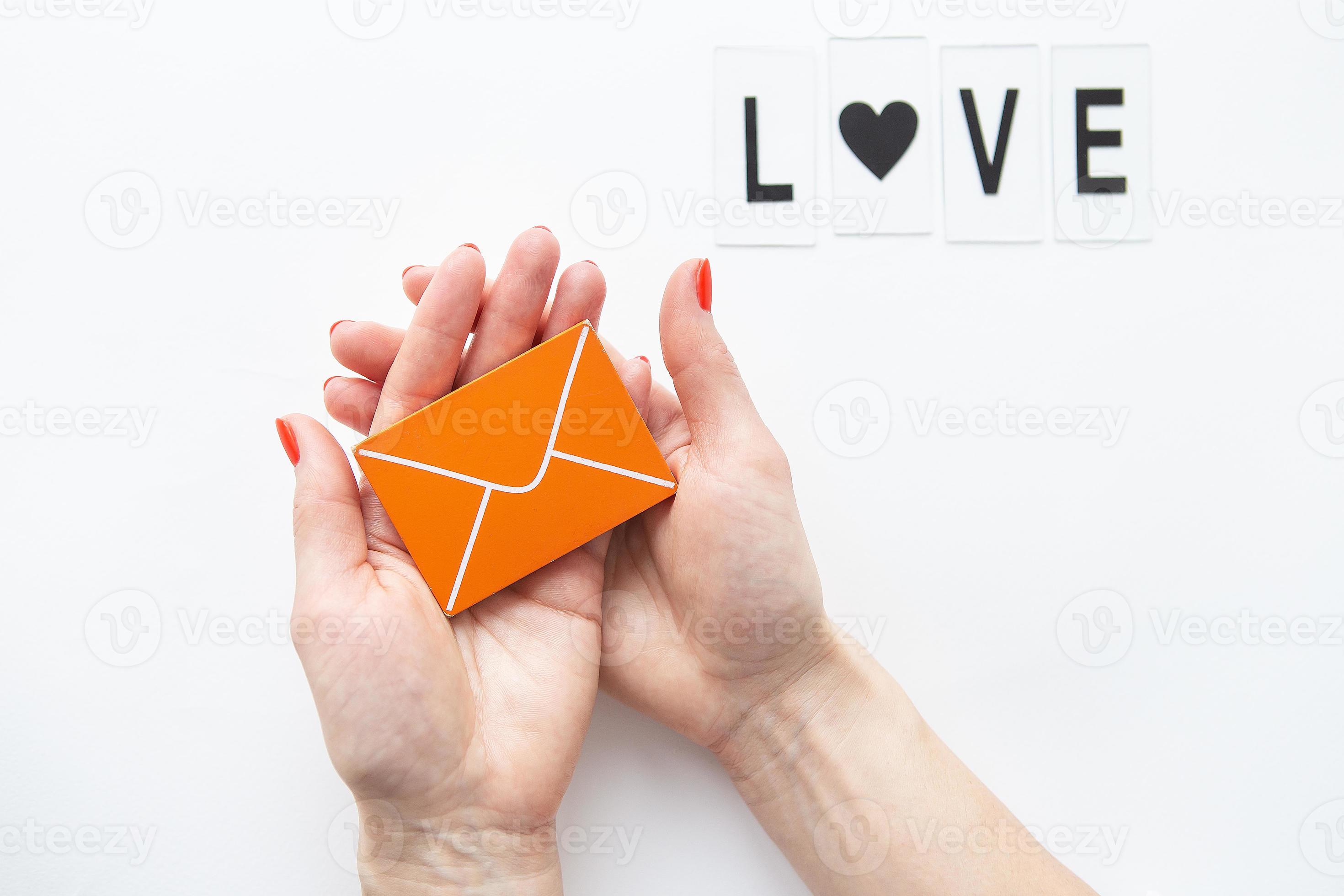 une lettre d'amour tenant une petite enveloppe orange en bois