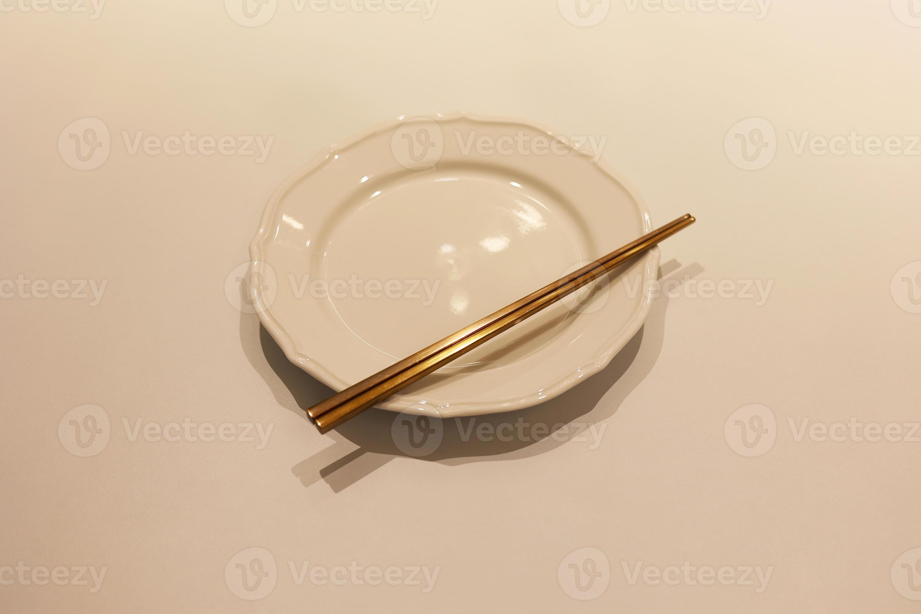 un ensemble de baguettes coréennes en laiton avec un plat blanc vide sur la  table, la baguette sur le plat 17668622 Photo de stock chez Vecteezy