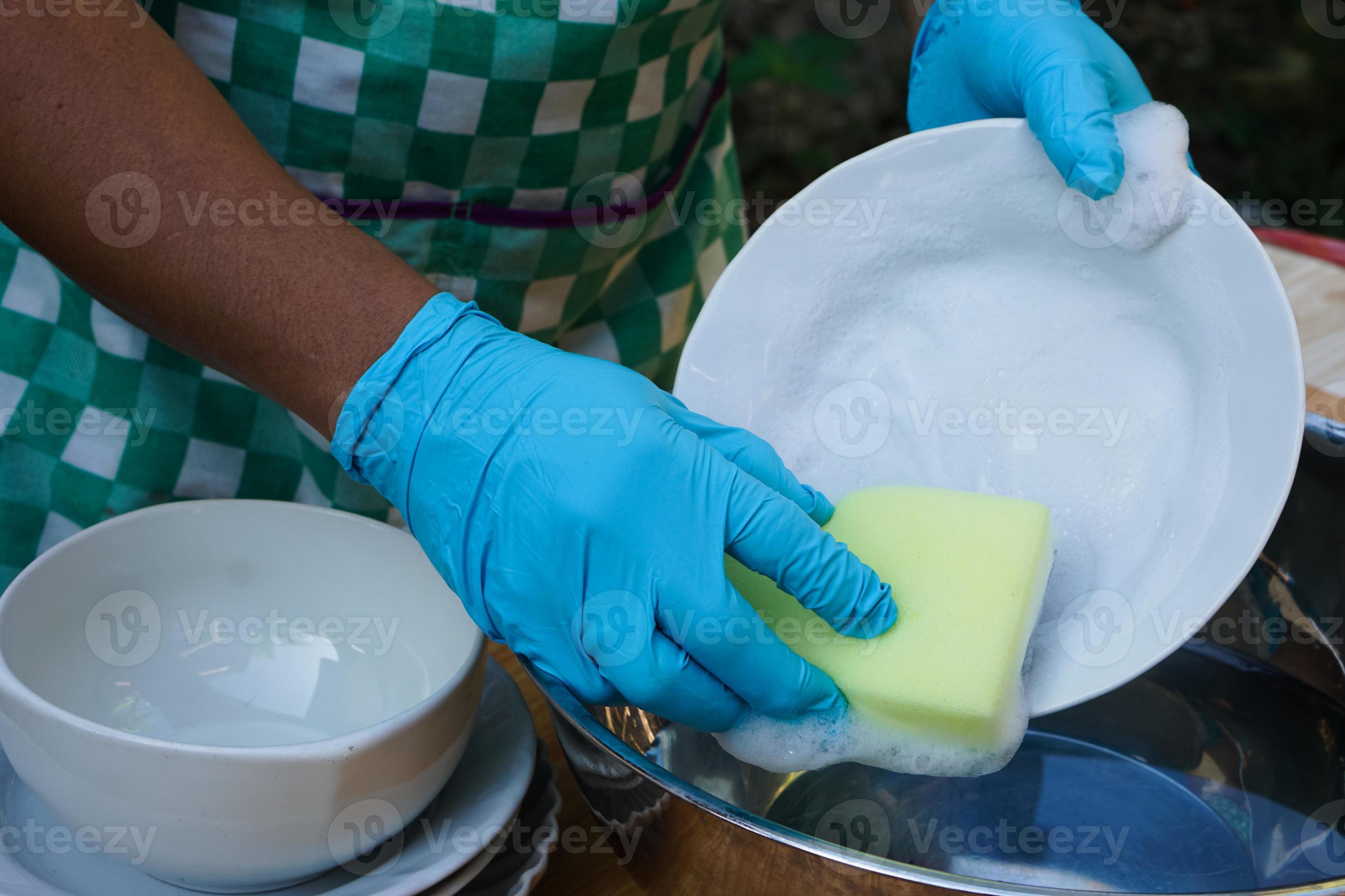 les mains utilisent un épurateur éponge pour nettoyer le plat. concept,  corvée quotidienne, ustensiles de cuisine de nettoyage domestique. porter  des gants de protection pour se protéger les mains des allergies aux
