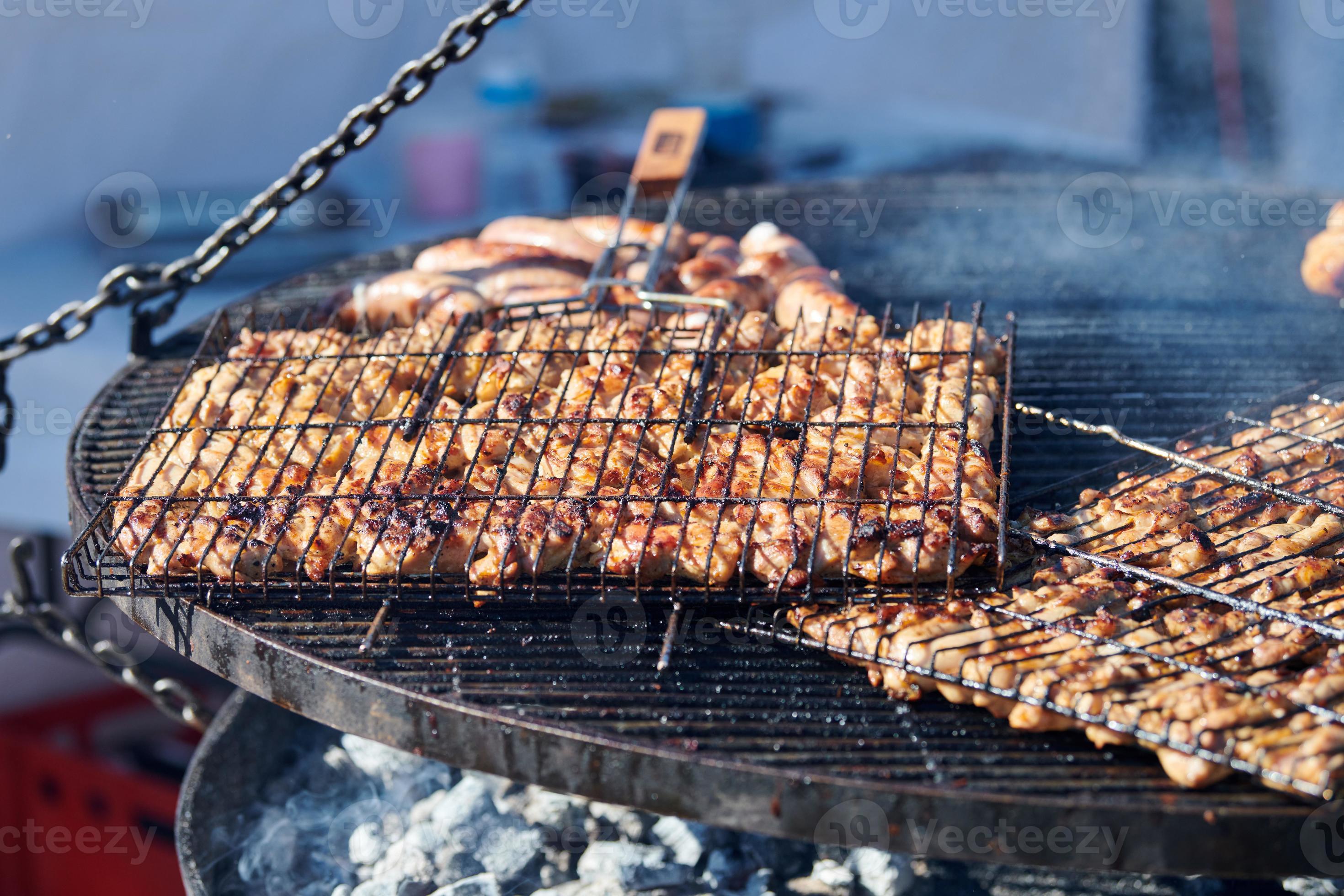 cuisson du poulet barbecue sur un panier de barbecue avec manche