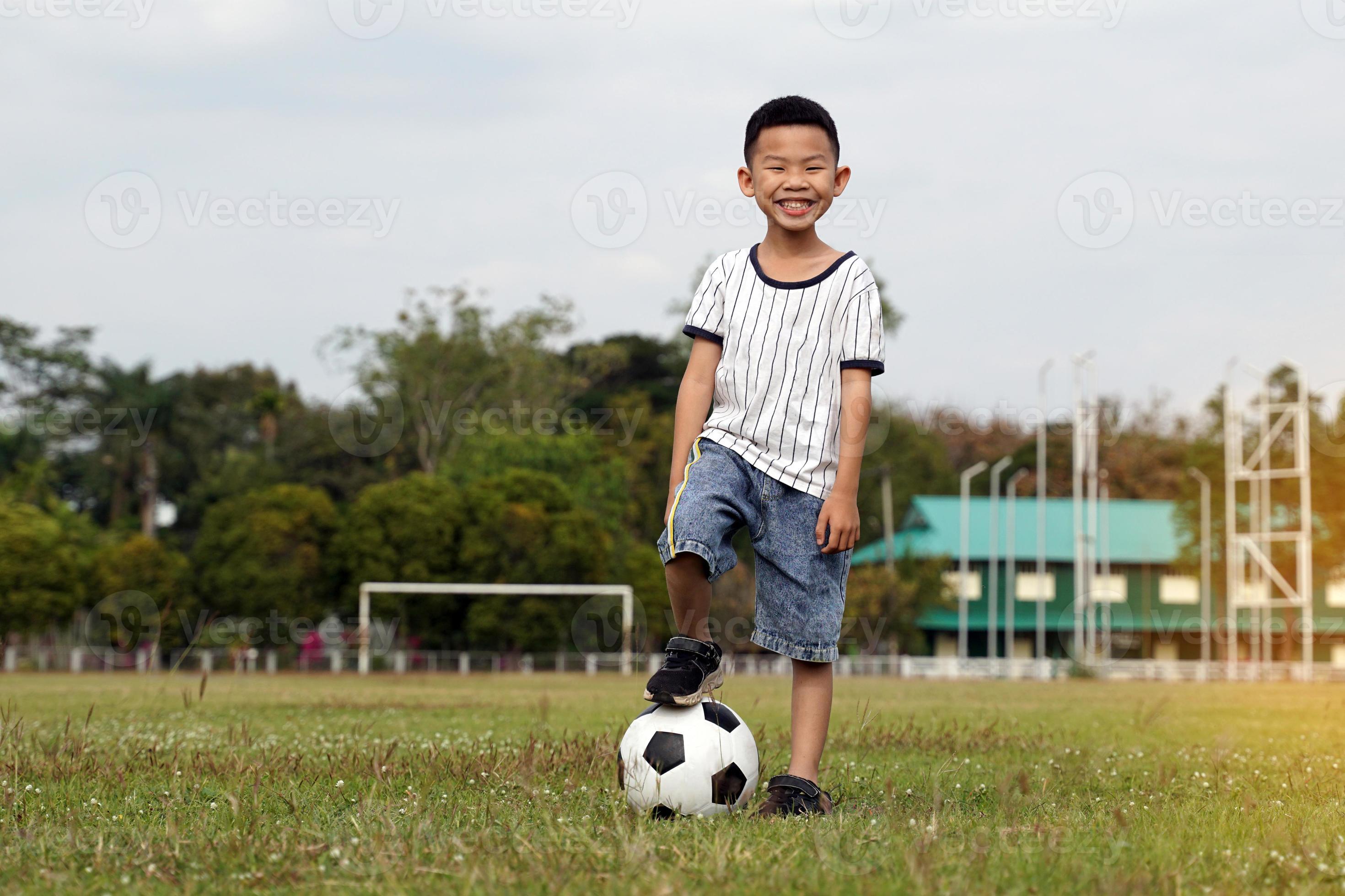 garçon asiatique marchant sur un ballon tout en donnant un coup de pied au  football sur le terrain. mise au point douce et sélective. 21032965 Photo  de stock chez Vecteezy