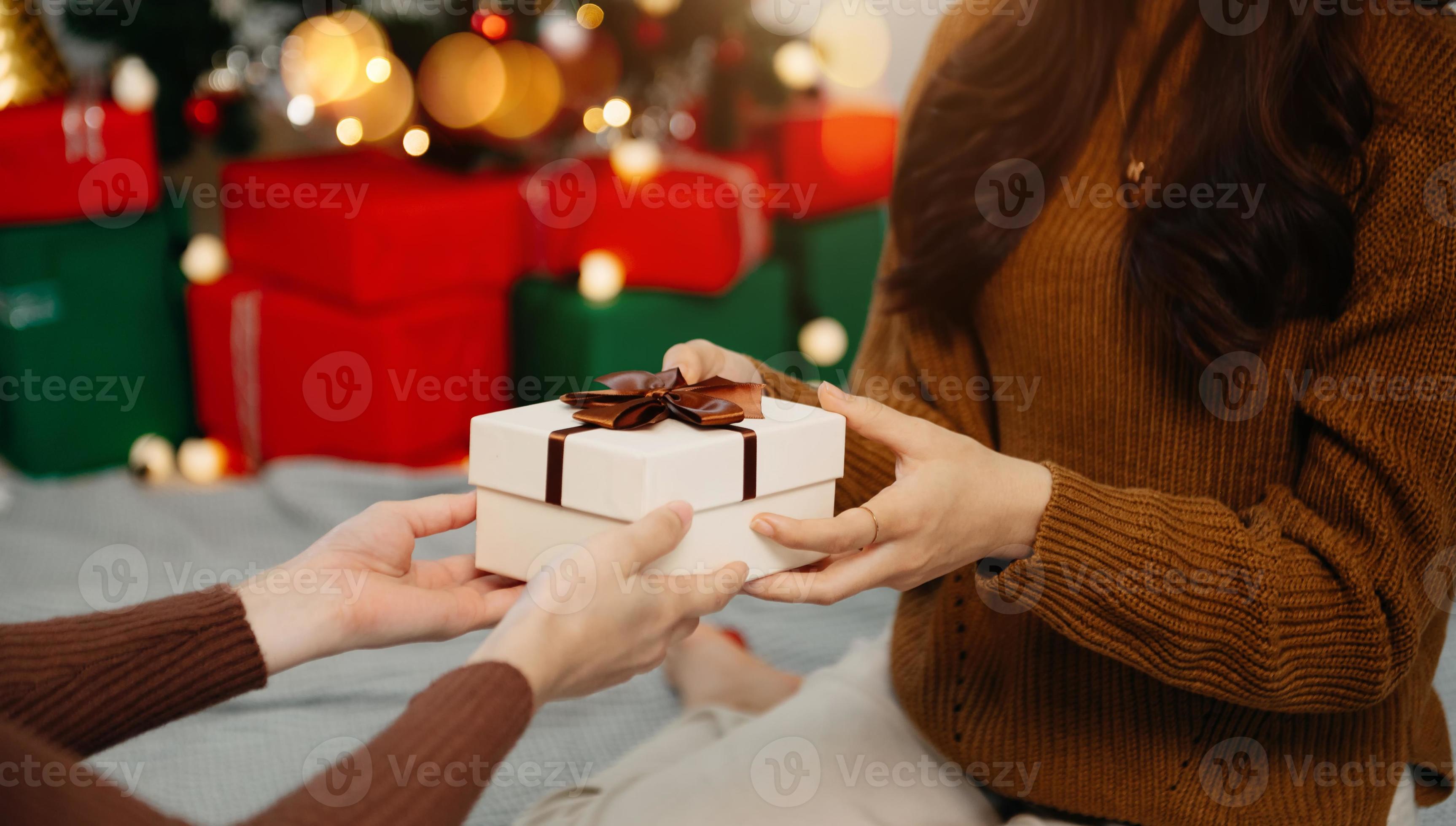 femme heureuse donnant une boîte-cadeau de noël et du nouvel an à une femme  à la maison.célébration de noël en famille. décoration de Noël. 19038795  Photo de stock chez Vecteezy