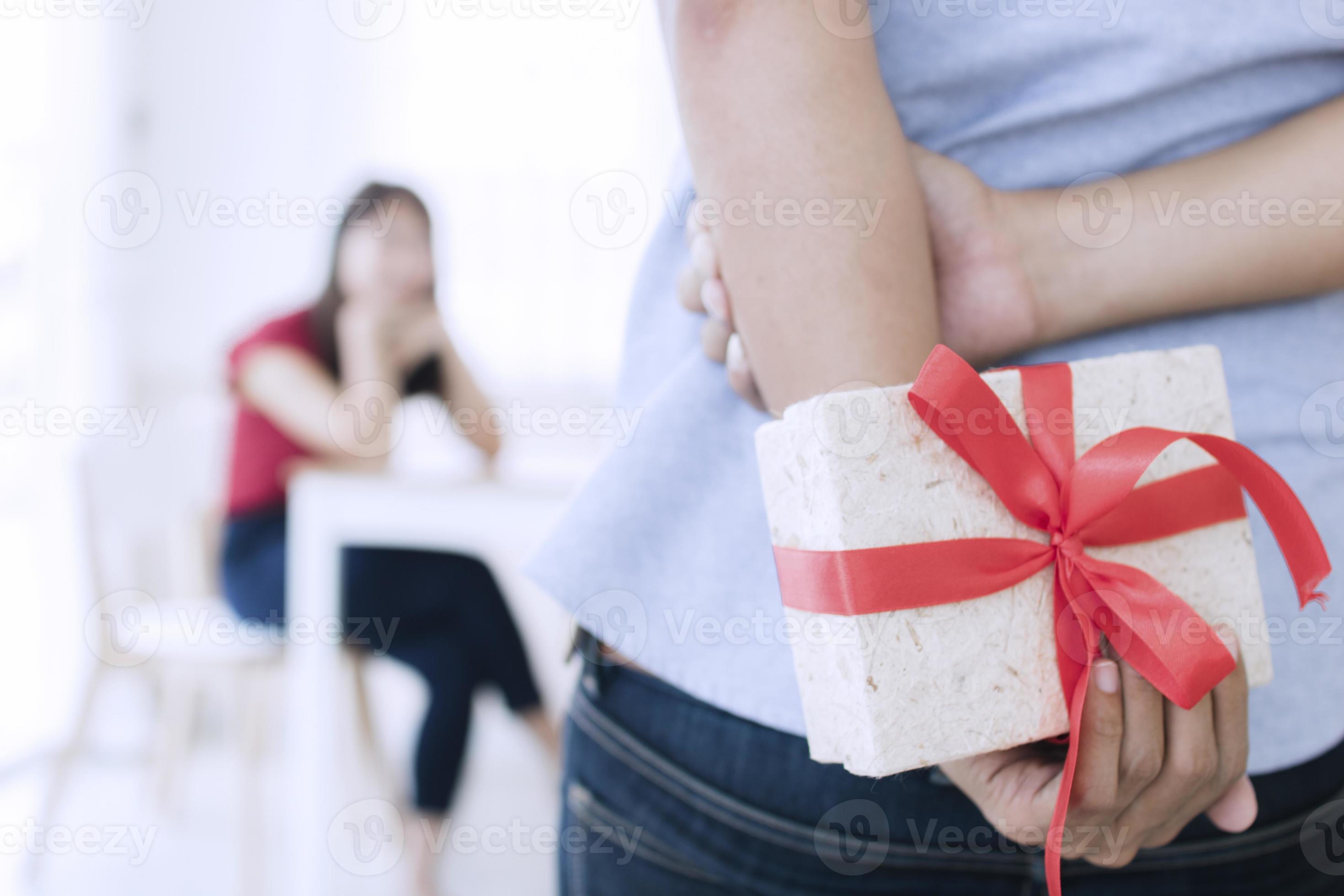 personne tenant un cadeau dans le dos photo