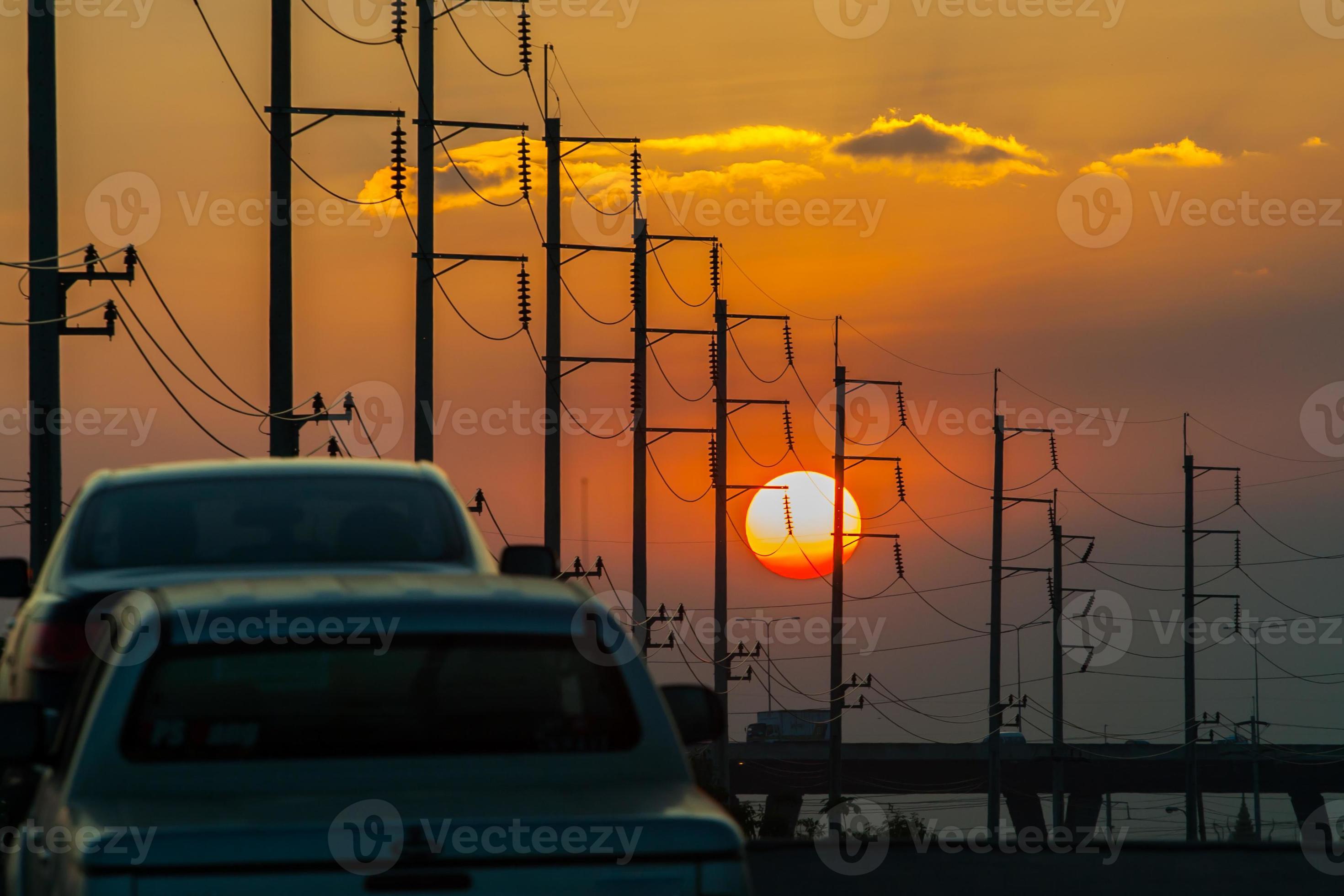 voitures et poteaux électriques au coucher du soleil photo