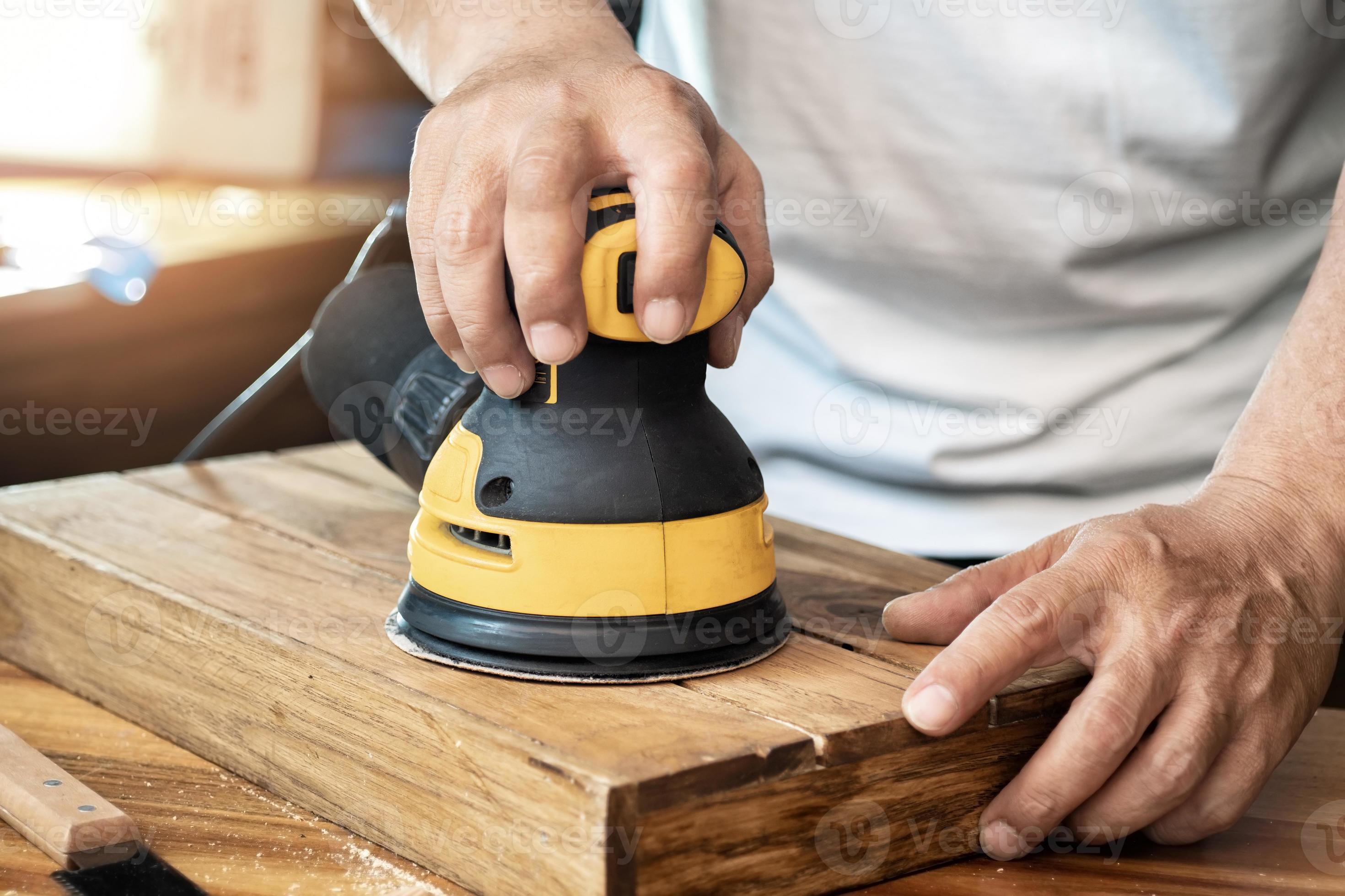 le charpentier utilise une ponceuse à orbite aléatoire ou une ponceuse à paume  polit le bois dans l'atelier, le fabricant de bricolage et le concept de  menuiserie. mise au point sélective 20410499