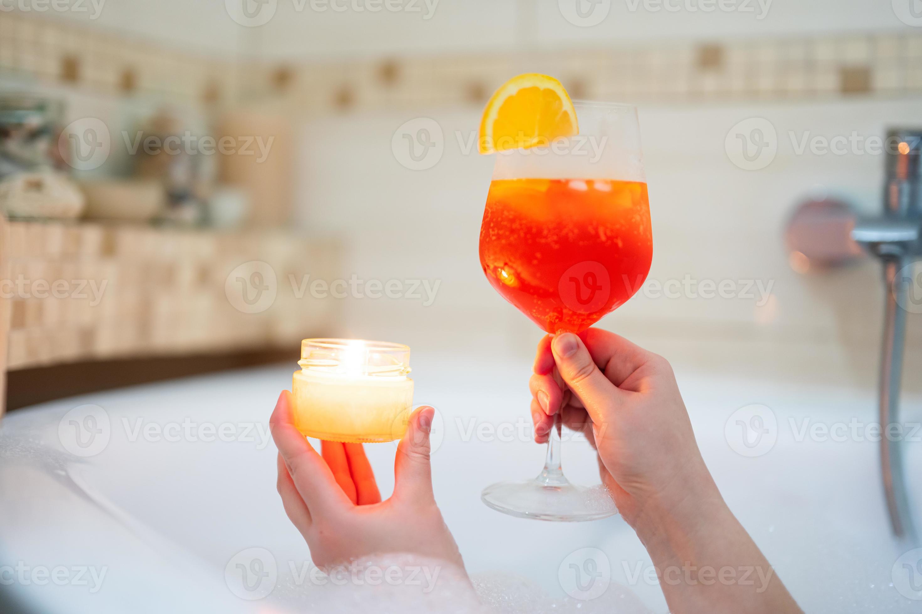 femme en portant verre de aperol spritz ou coctail dans une baignoire avec  arôme bougie. 20819616 Photo de stock chez Vecteezy