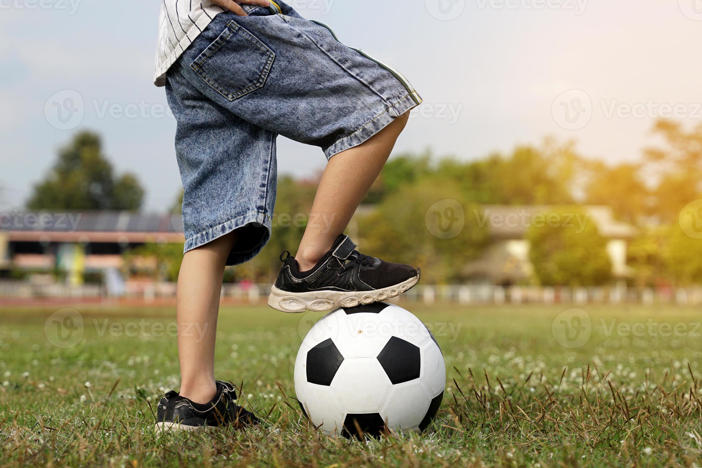 garçon asiatique marchant sur un ballon tout en donnant un coup de pied au  football sur le terrain. mise au point douce et sélective. 21032965 Photo  de stock chez Vecteezy