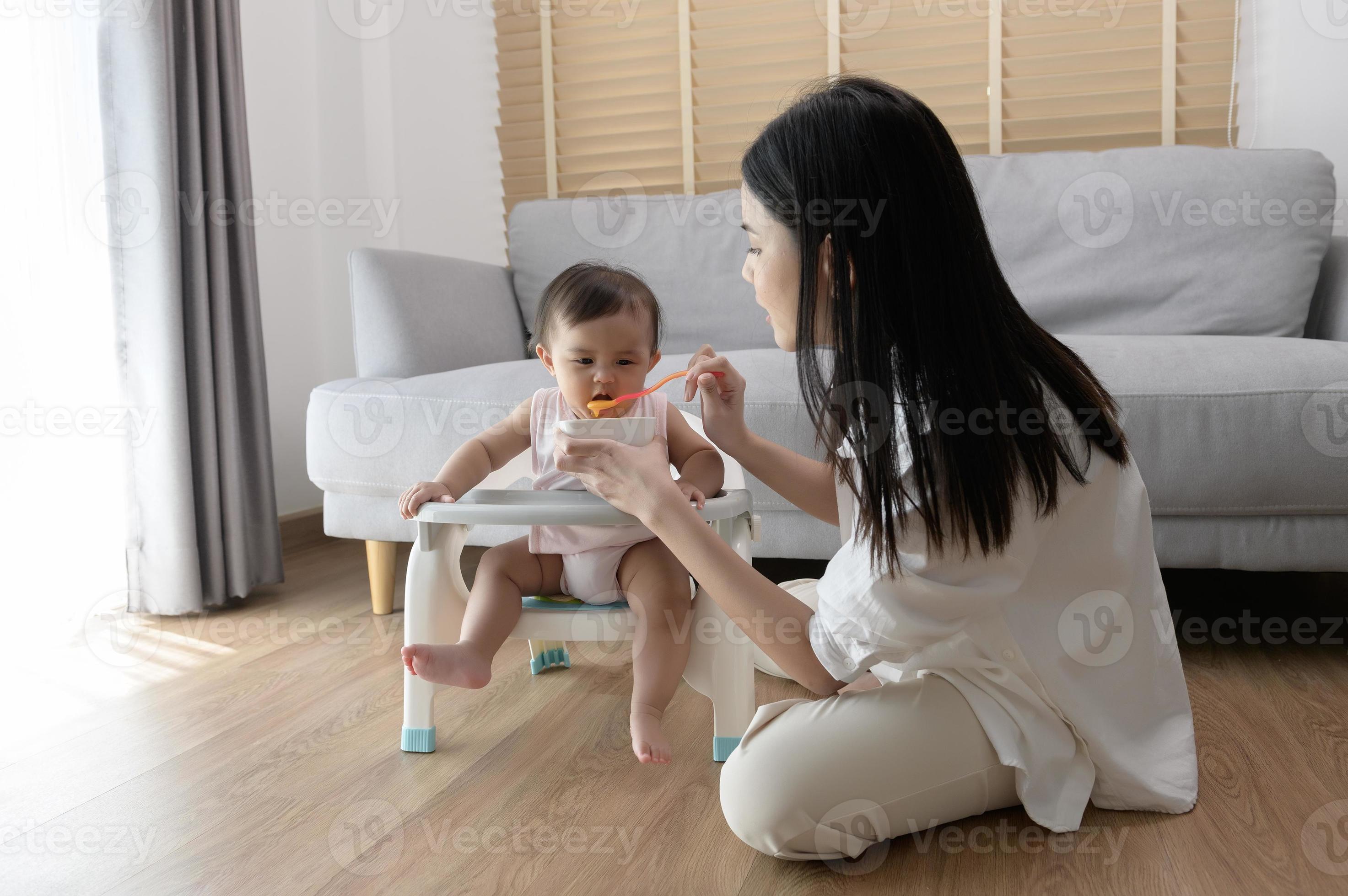 Jeune mère portion bébé en mangeant mélange nourriture sur bébé chaise  21697932 Photo de stock chez Vecteezy