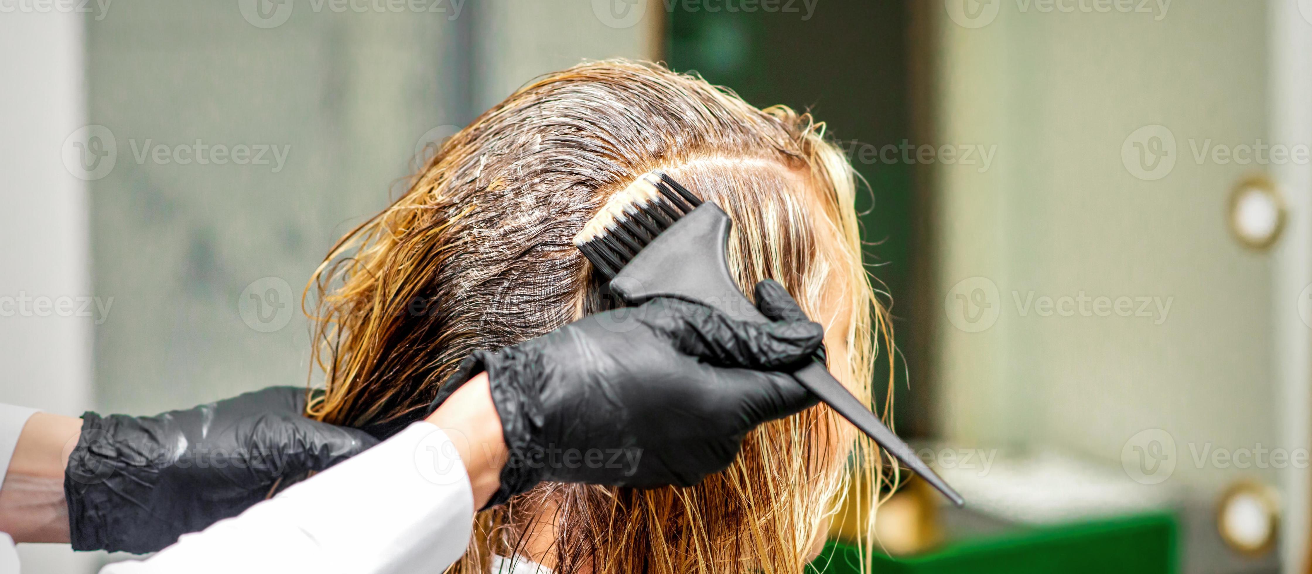 main de une coiffeur dans noir gants appliquant colorant à le femelle  cheveux dans une beauté salon. 22677369 Photo de stock chez Vecteezy