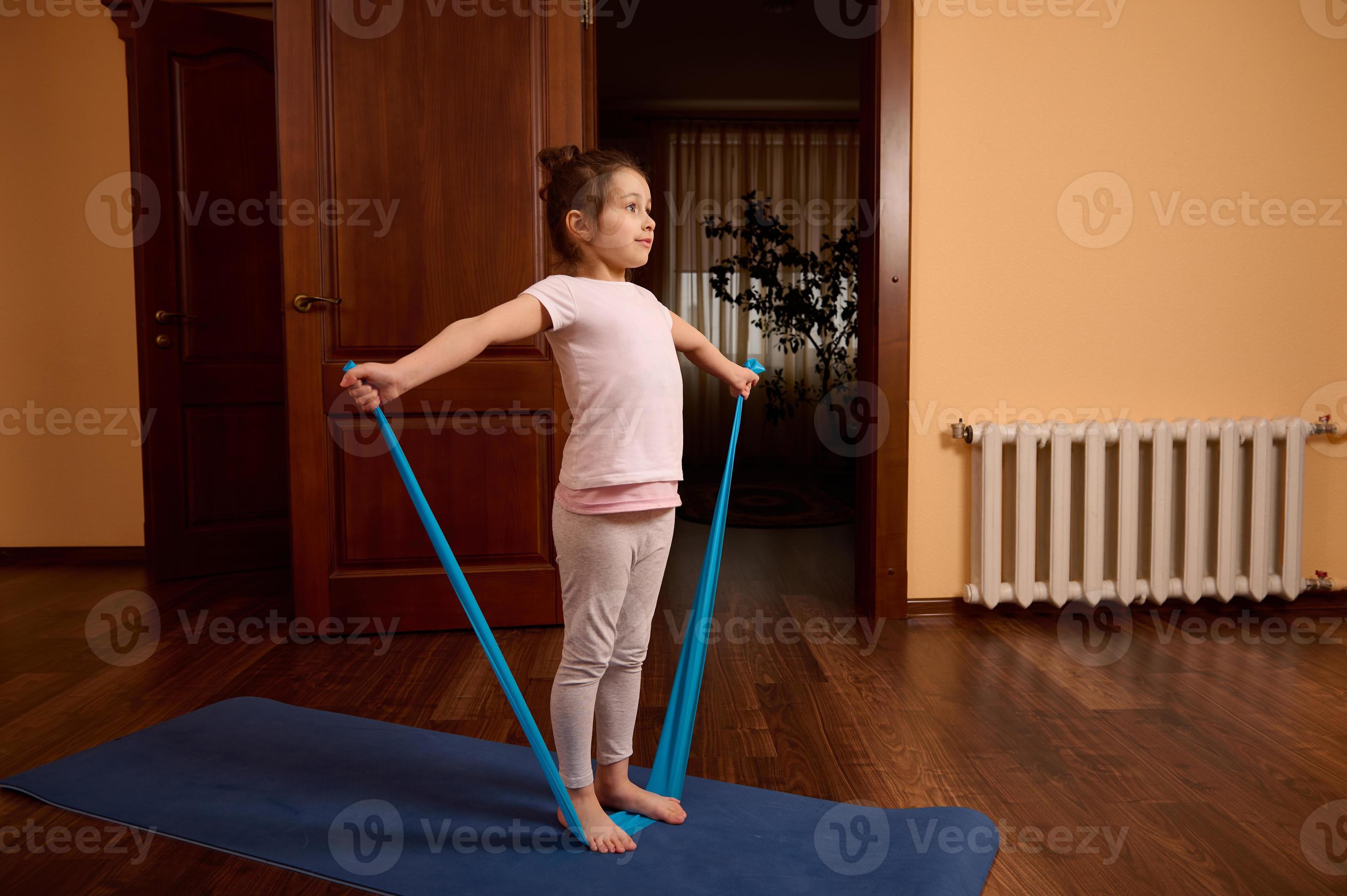 https://static.vecteezy.com/ti/photos-gratuite/p2/22971473-peu-enfant-fille-dans-tenue-de-sport-permanent-sur-une-gym-tapis-et-faire-elongation-des-exercices-sur-bras-avec-elastique-bande-a-accueil-photo.jpg