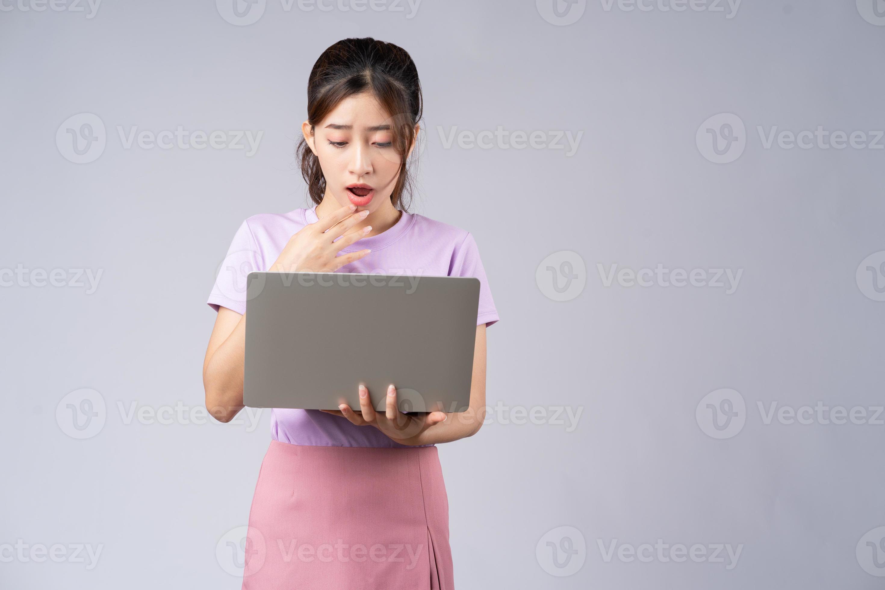 jeune femme asiatique utilisant un ordinateur portable sur fond gris photo