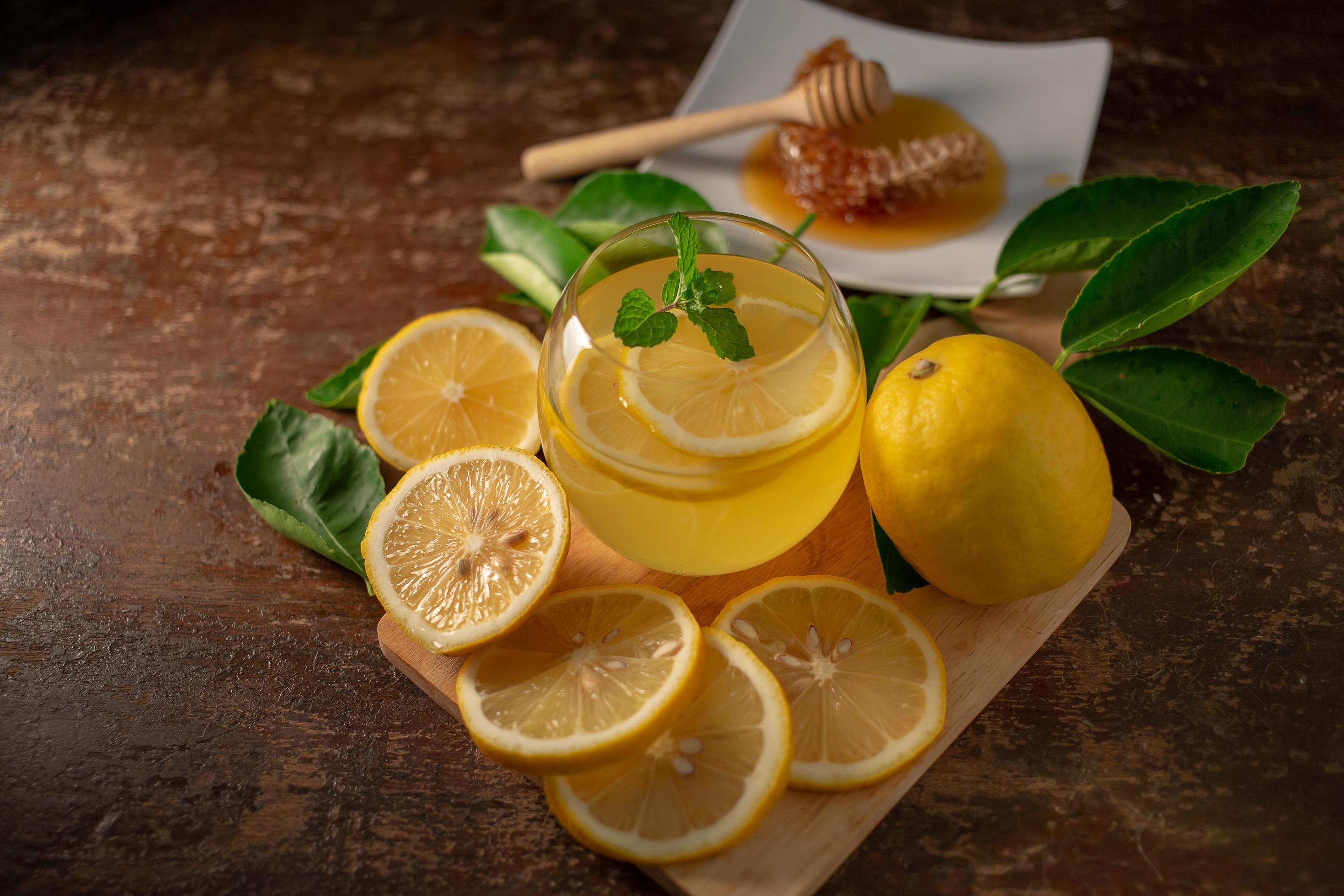 jus de citron au miel sur table en bois, citrons et feuilles de sauge photo