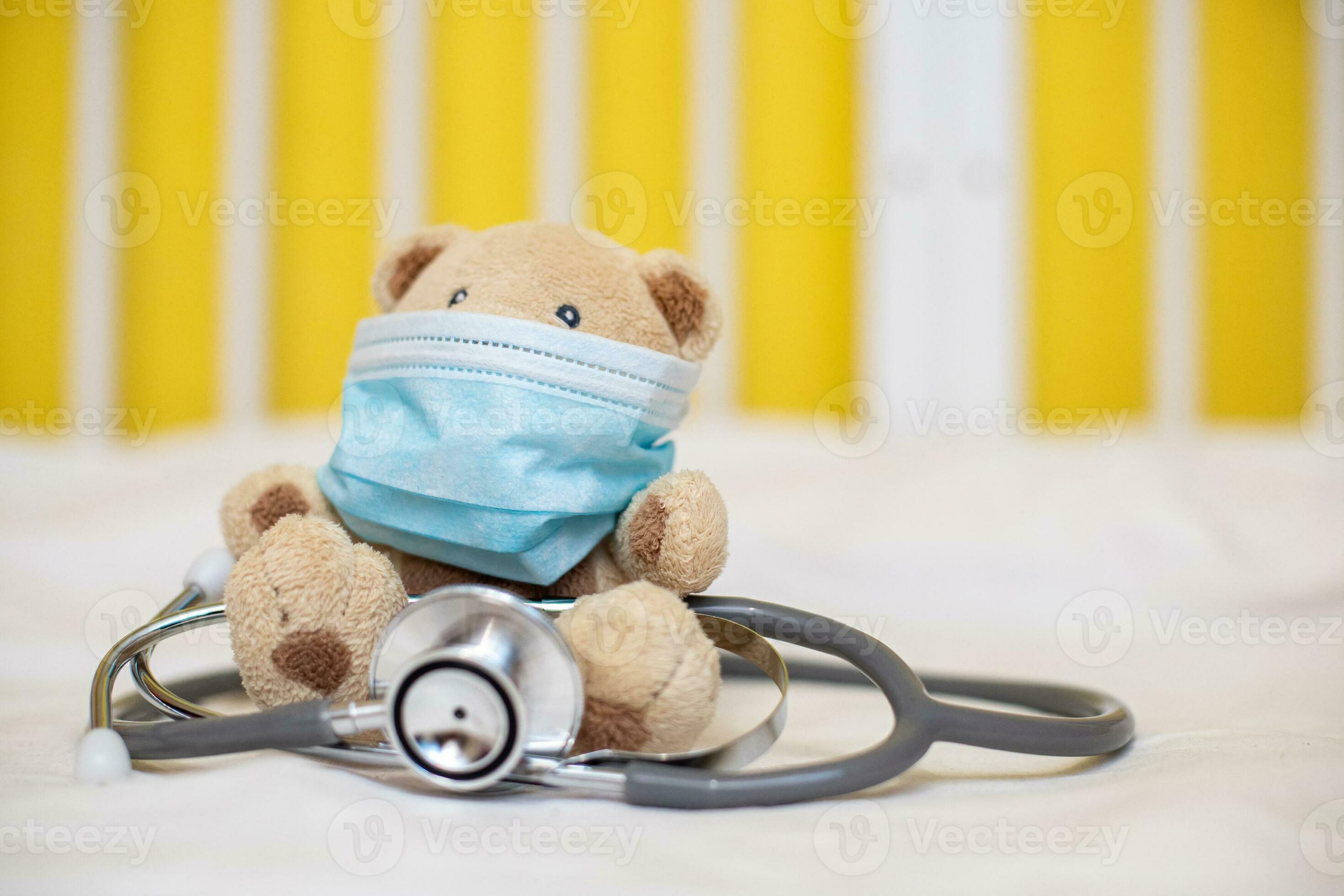 Bébé Dans Un Masque Médical Joue Avec Un Ours En Peluche. Bébé