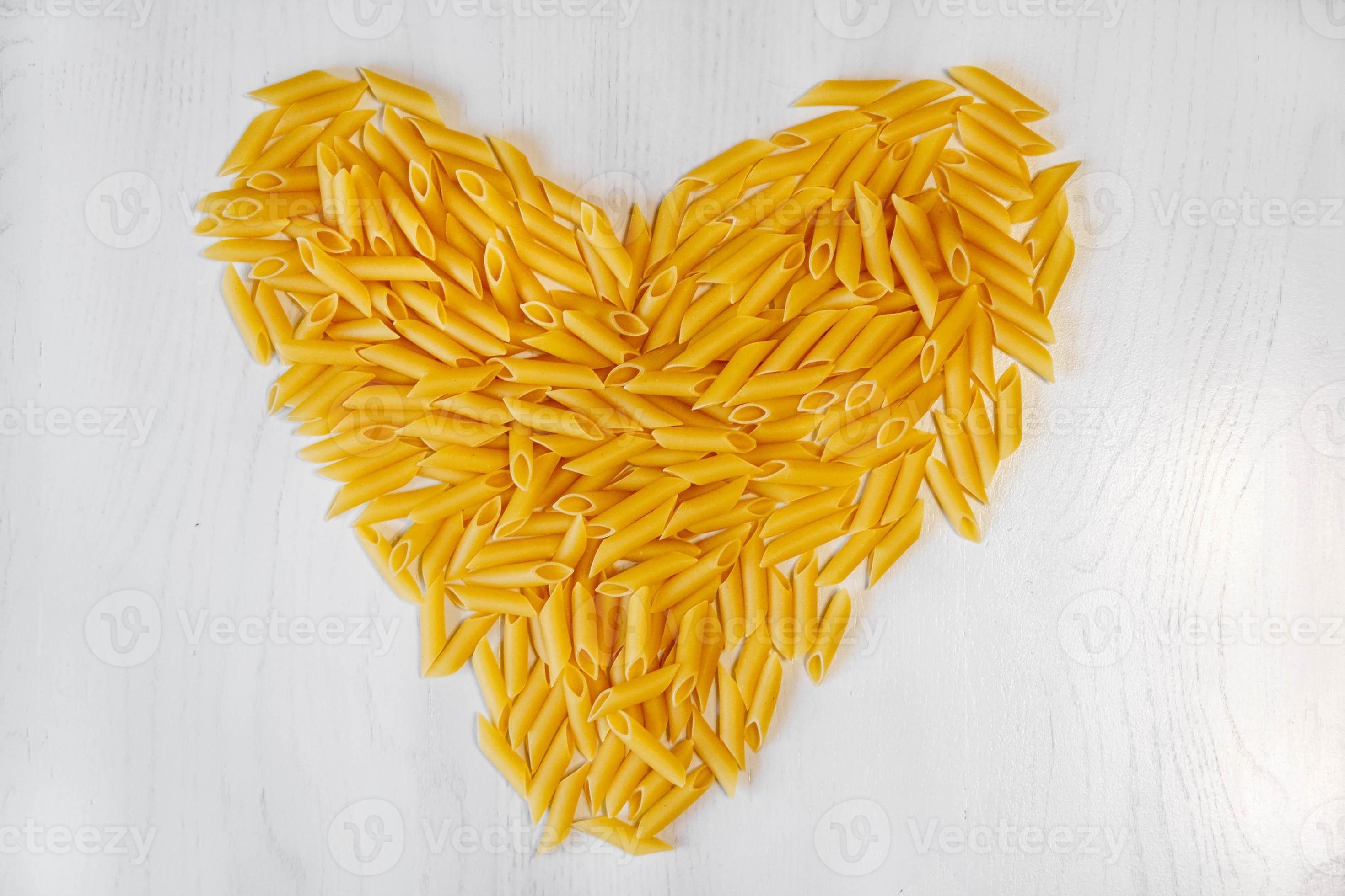 penne rigate de pâtes en forme de coeur sur une table en bois de fond blanc  4718111 Photo de stock chez Vecteezy