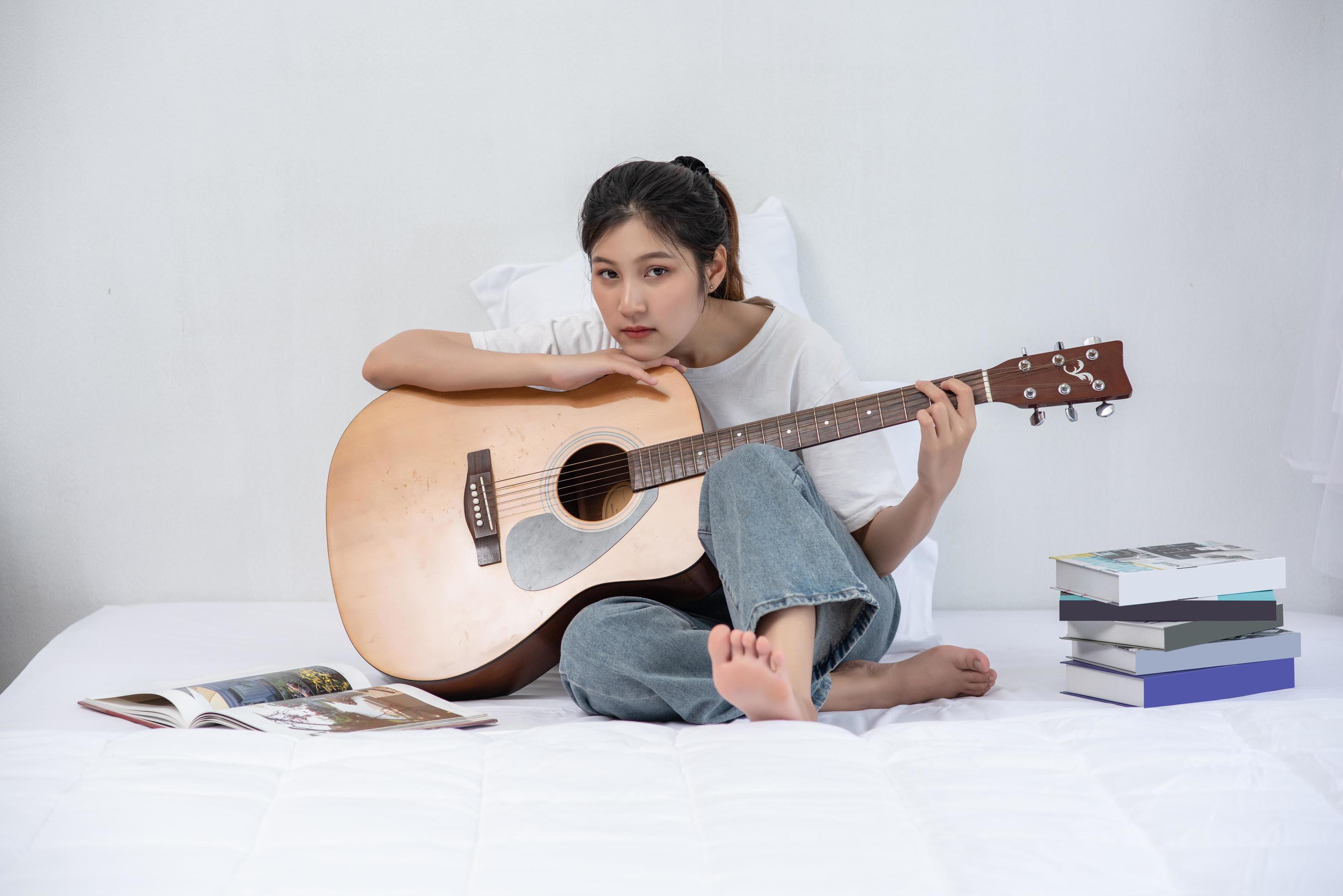 la fille s'est assise et a joué de la guitare sur le lit. 4890519 Photo de  stock chez Vecteezy