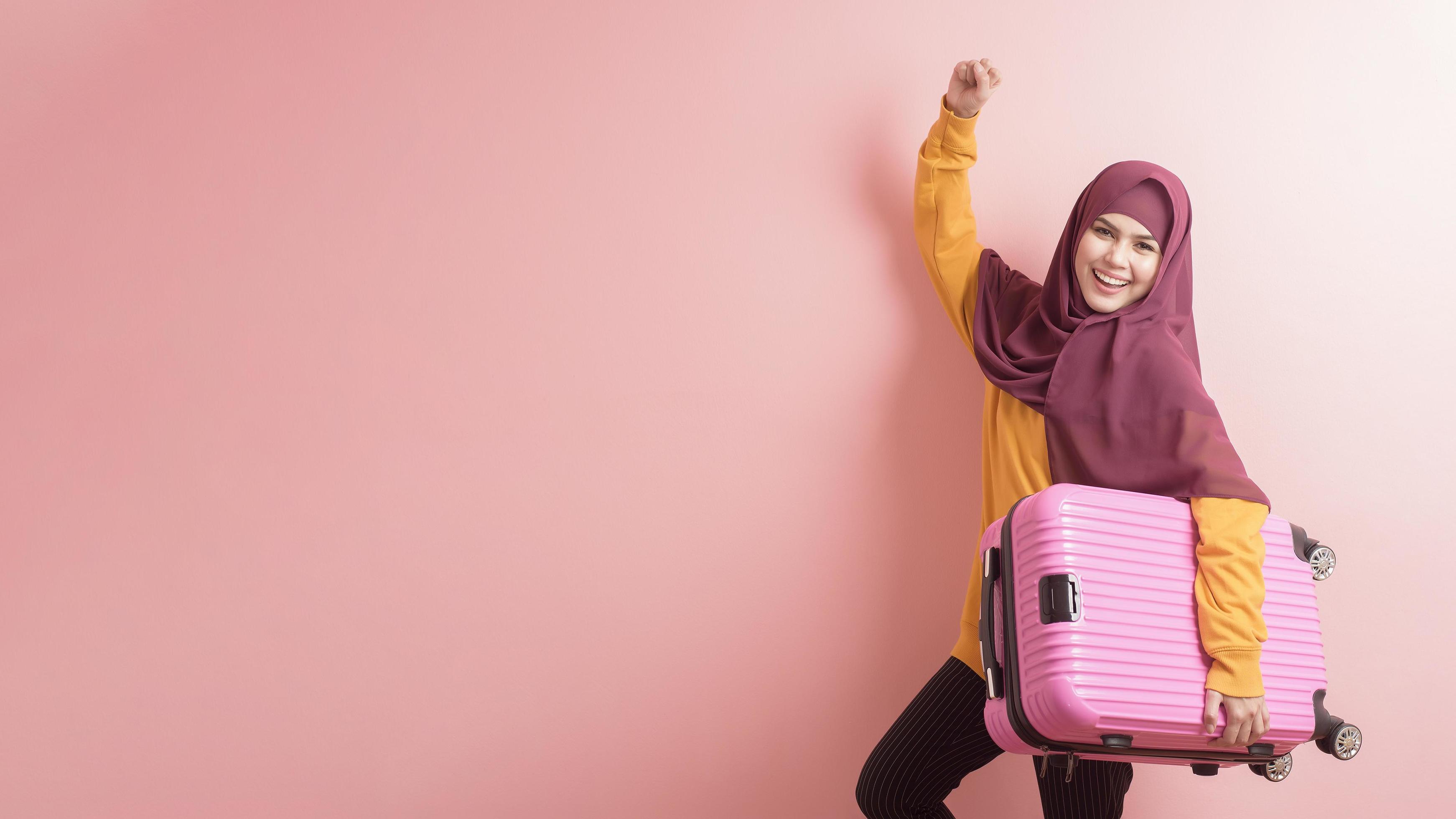 femme musulmane avec hijab tient des bagages sur fond rose, les gens voyagent concept photo