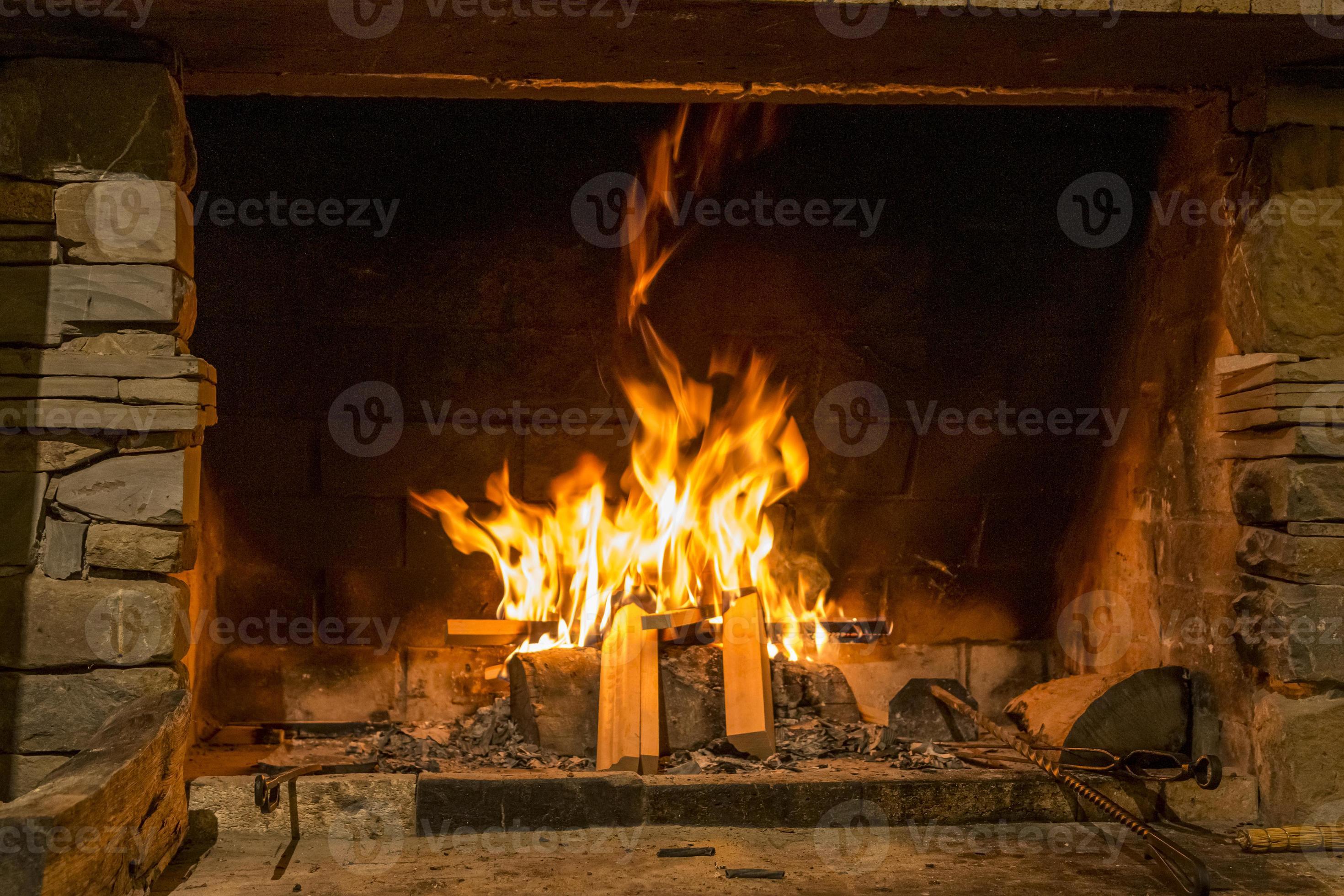 grande cheminée en pierre avec feu brûlant et bois de chauffage sur support  en métal. moments chaleureux et calmes à la saison froide, chauffage dans  la cabine. 5509408 Photo de stock chez