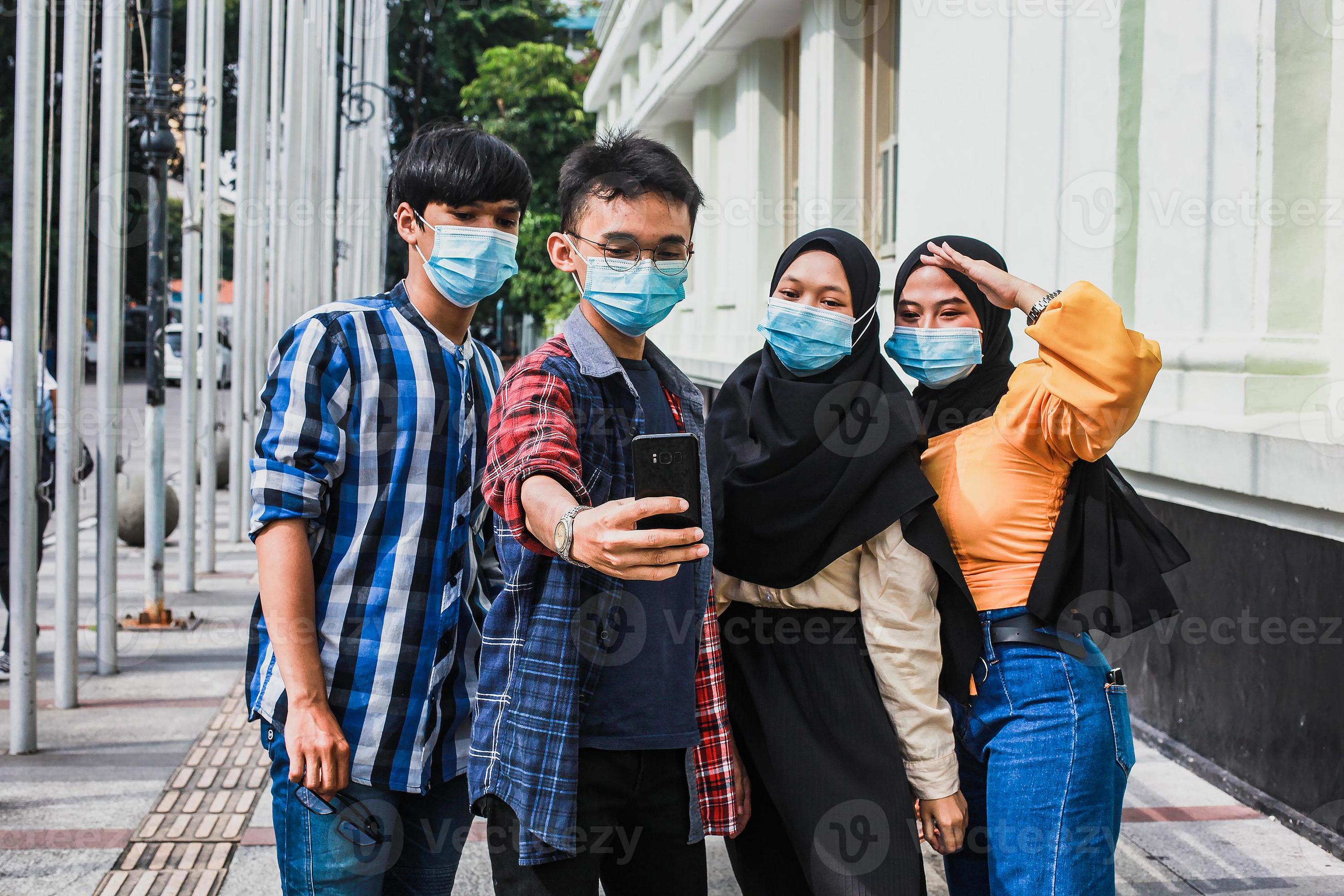 amis avec masque de protection s'amusant à prendre des selfies pendant la pandémie du virus corona en été. photo