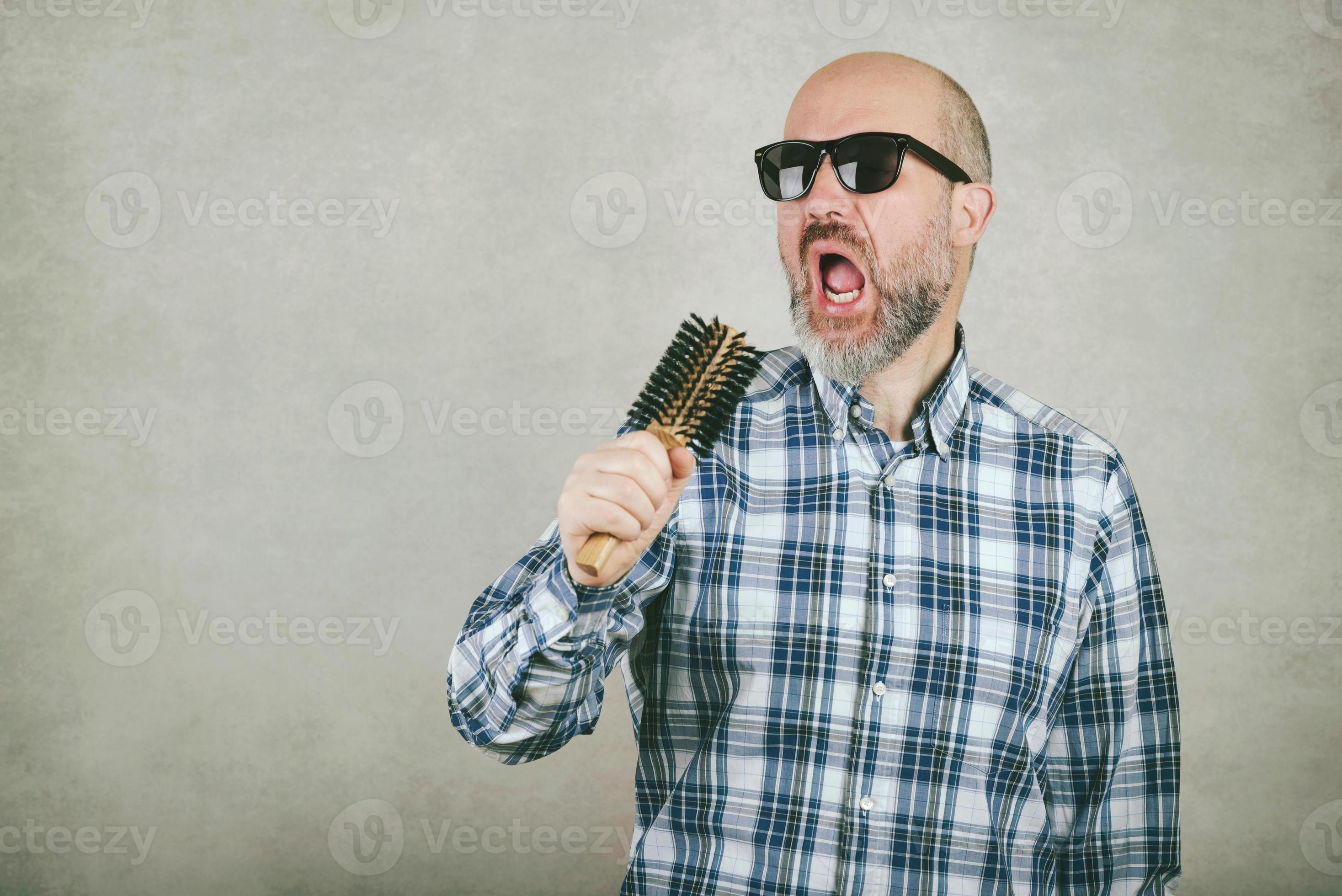 homme chauve avec des lunettes de soleil chantant une brosse à cheveux  6131660 Photo de stock chez Vecteezy