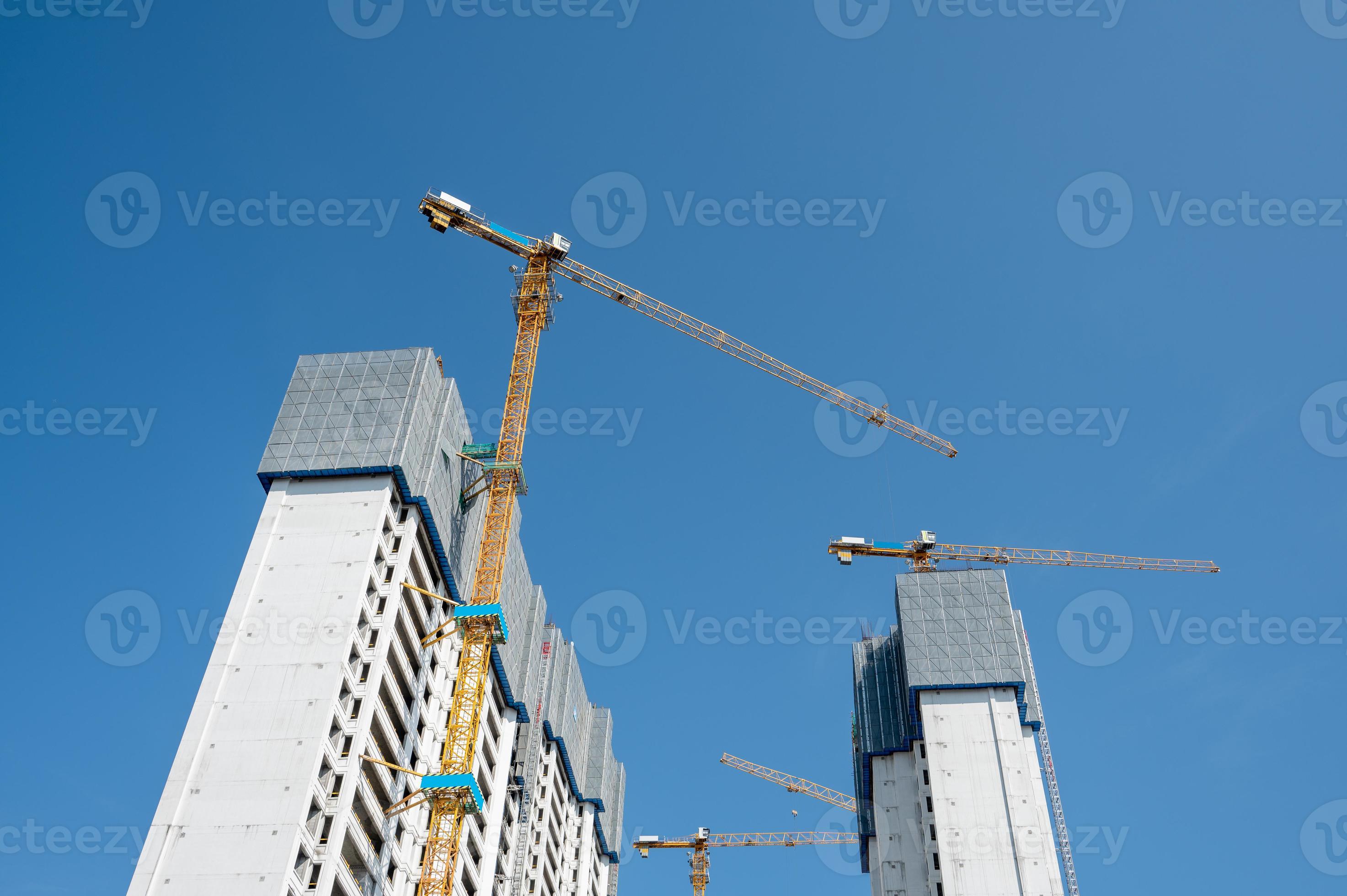 c'est une belle journée avec un ciel bleu, et la grue à tour sur les immeubles de grande hauteur de la ville est en construction photo