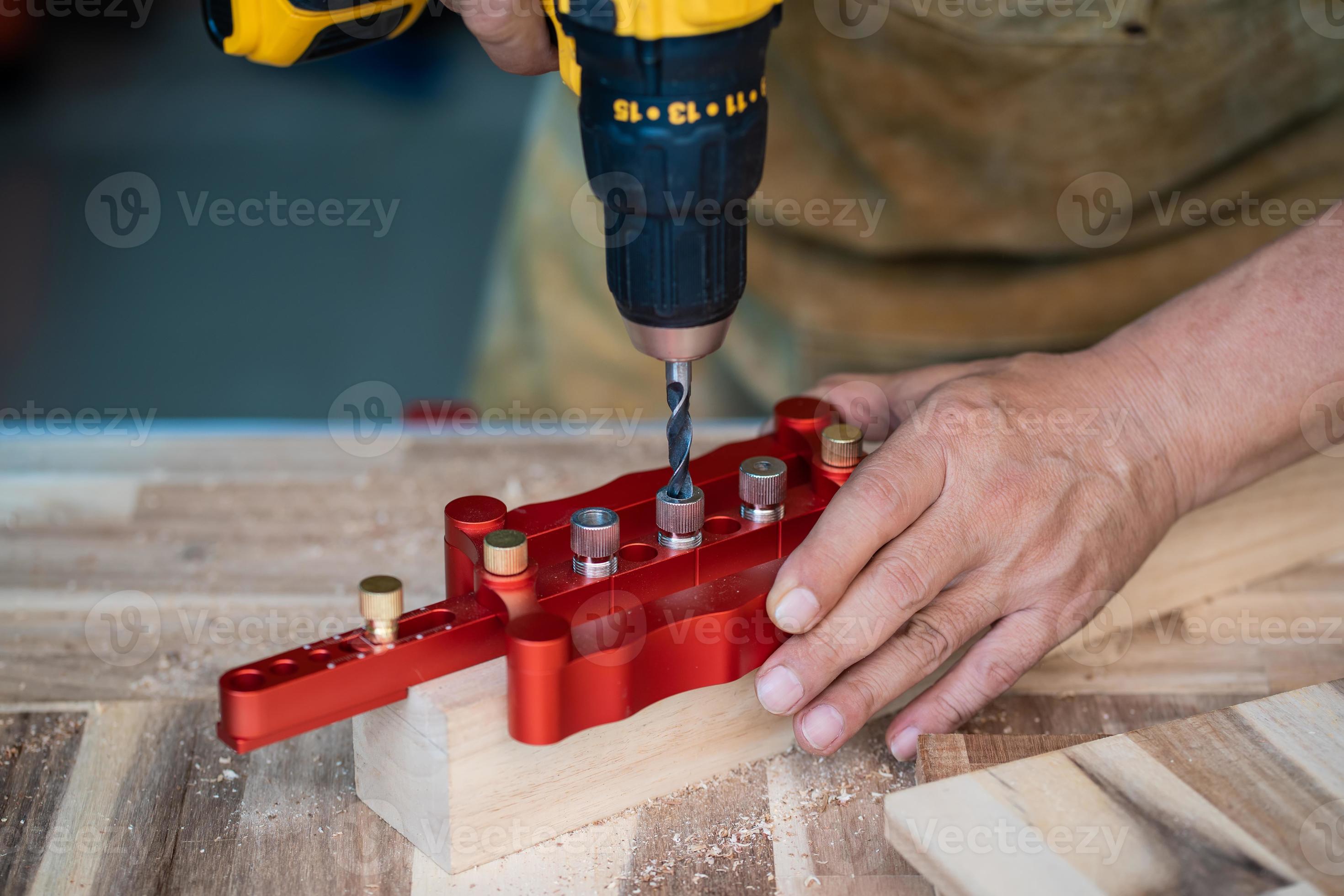 le charpentier utilise un foret et un gabarit de goujon de centrage ou un  outil de gabarit de trou de poche pour faire des joints solides sur une  plaque de bois. concept