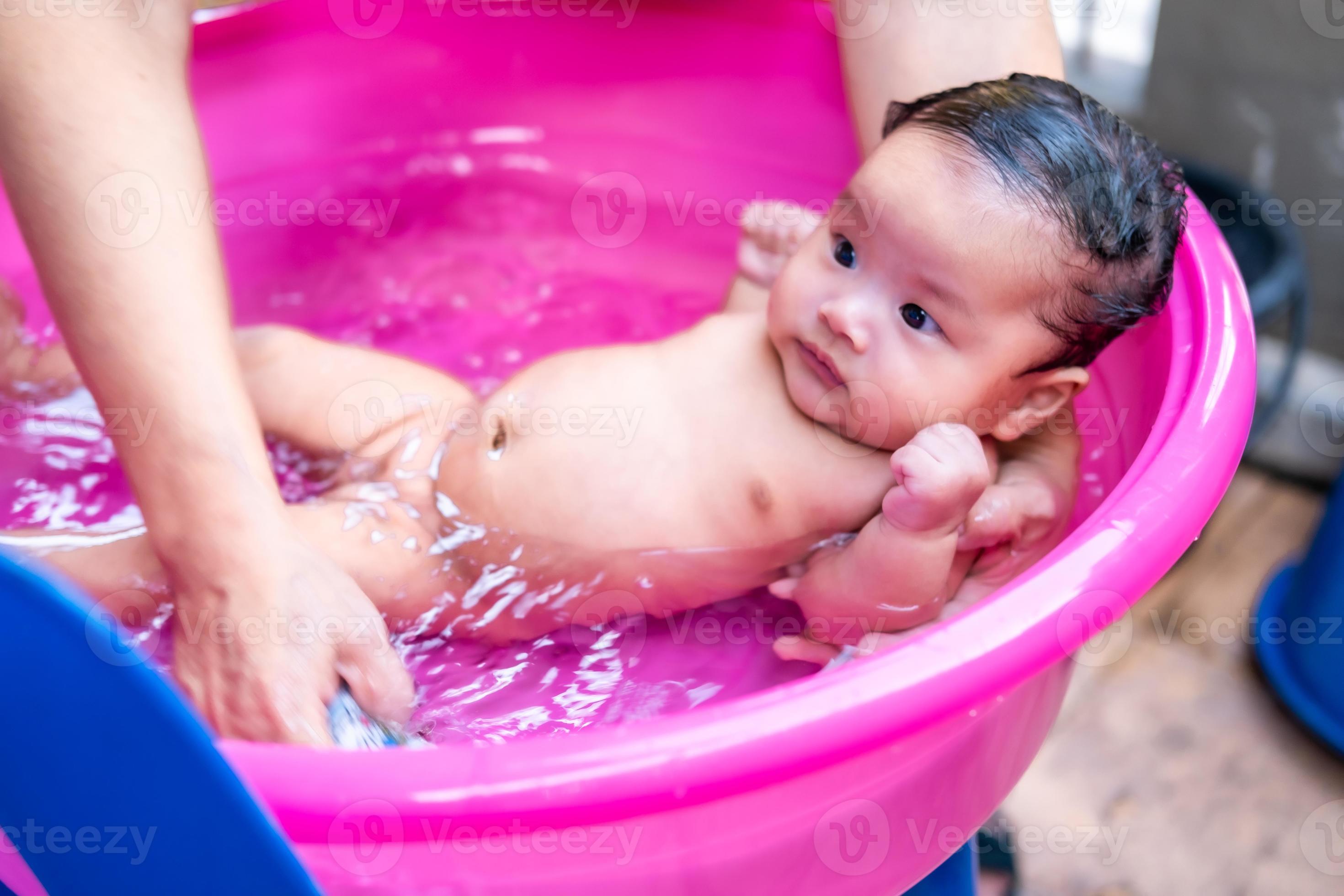 maman asiatique douche bébé pour nettoyer la saleté donner à l'enfant dans  le bain récipient