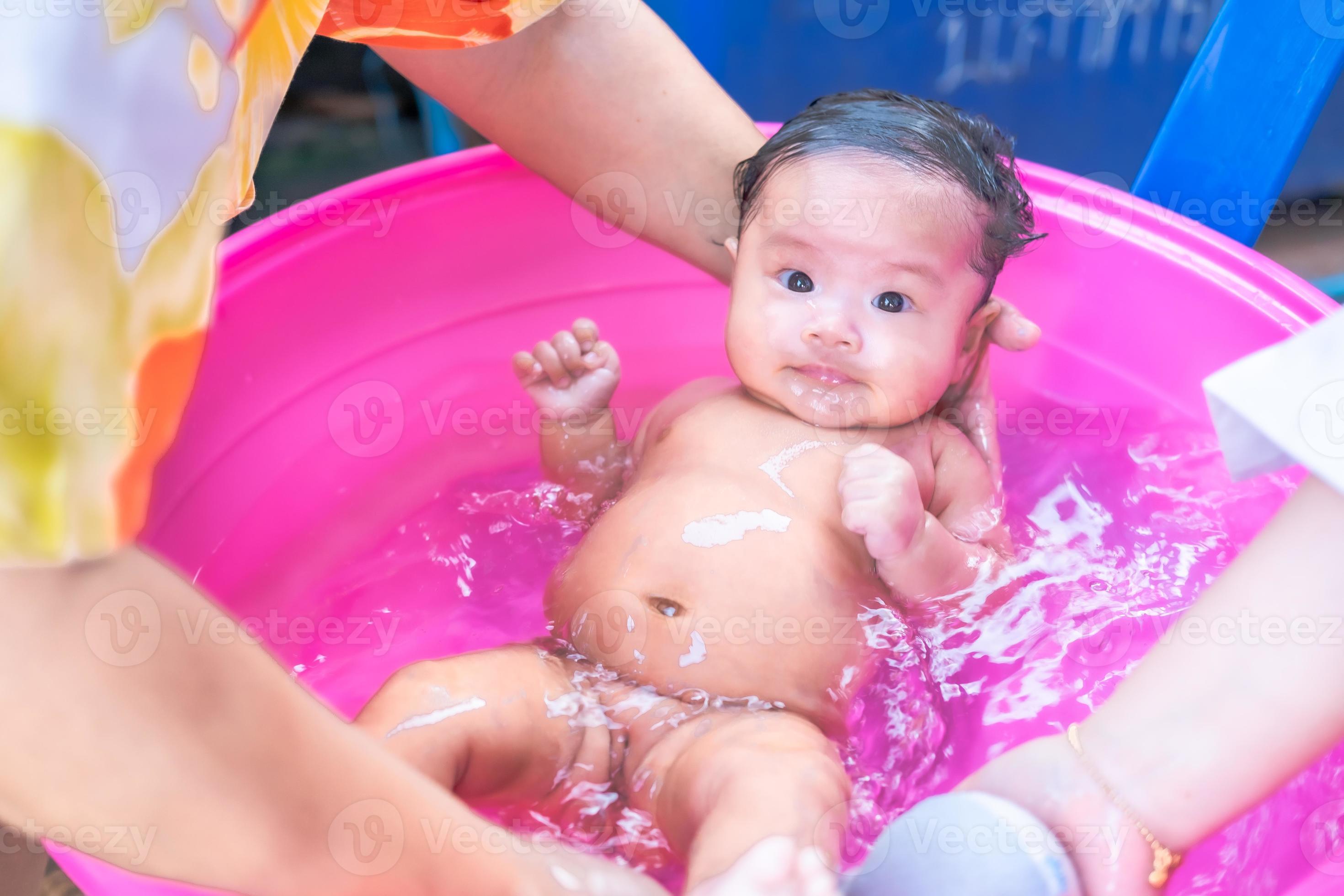 maman asiatique douche bébé pour nettoyer la saleté donner à l'enfant dans  le bain récipient