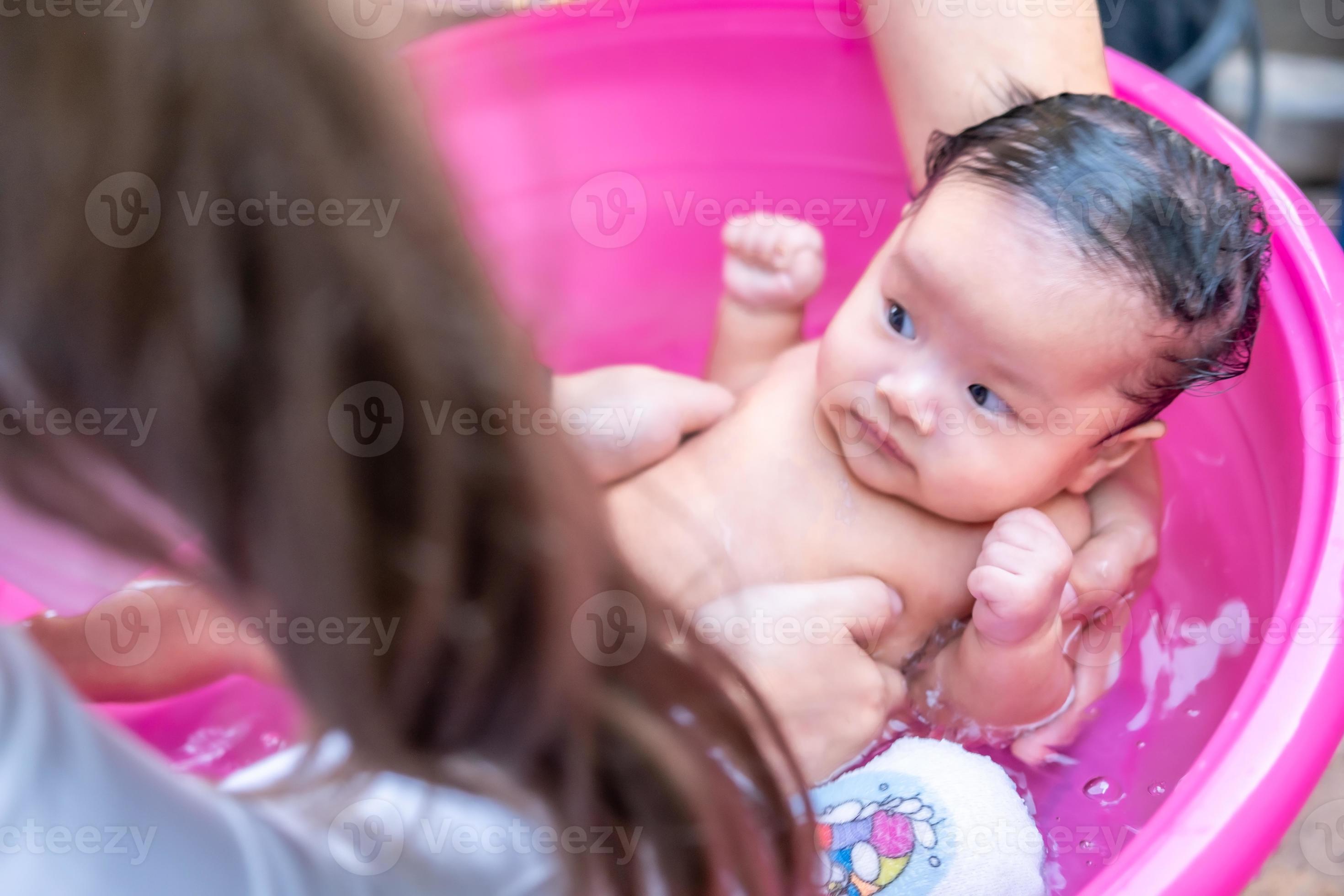 maman asiatique douche bébé pour nettoyer la saleté donner à l'enfant dans  le bain récipient