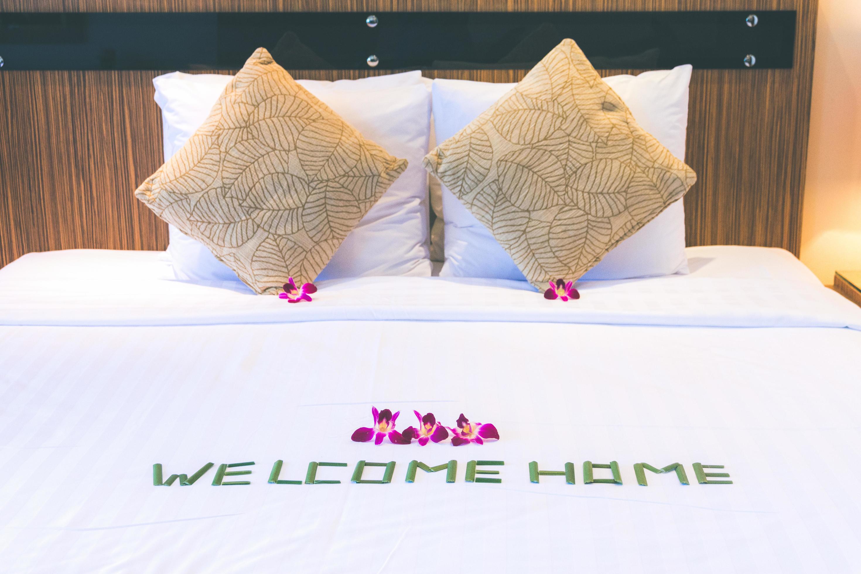 lit avec des oreillers décorés de fleurs tropicales et une inscription de bienvenue. thème du service hôtelier photo