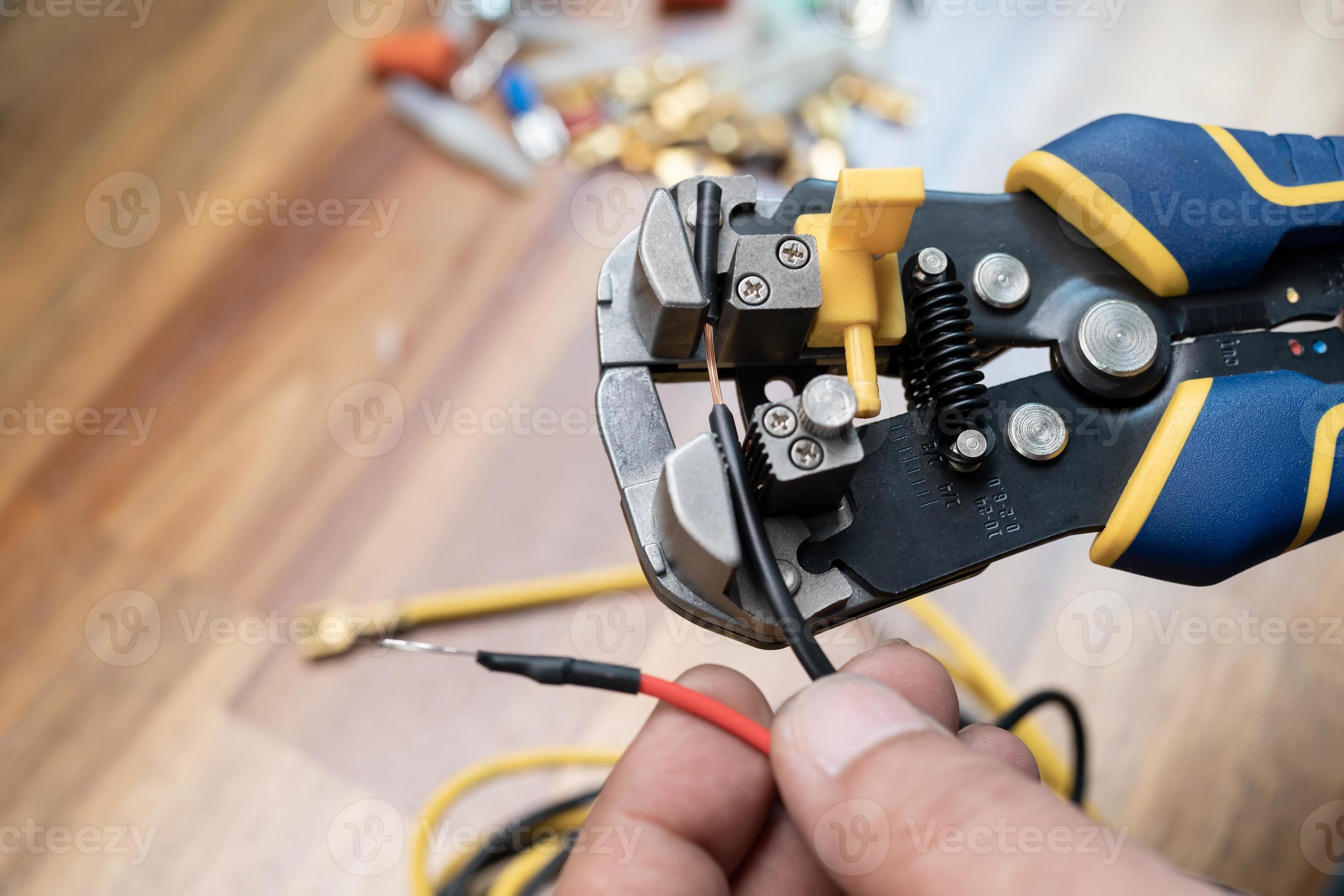 pince à dénuder ou pince à dénuder . électricien tenant un outil de  dénudage de câble pour enlever l'isolation des fils électriques.travailler  en toute sécurité et concept d'outils 7196357 Photo de stock