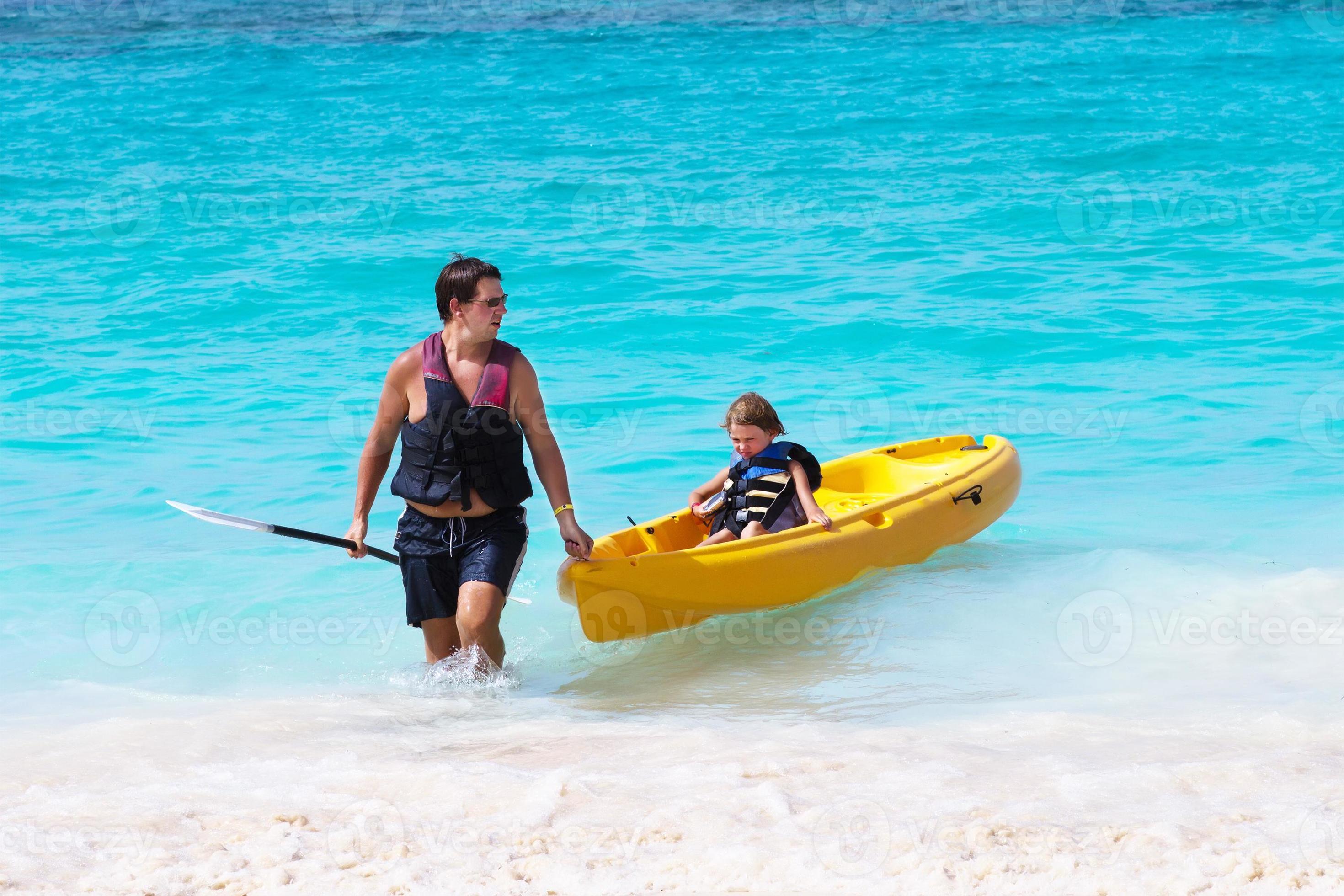 père et fils avec un kayak sur la plage tropicale photo