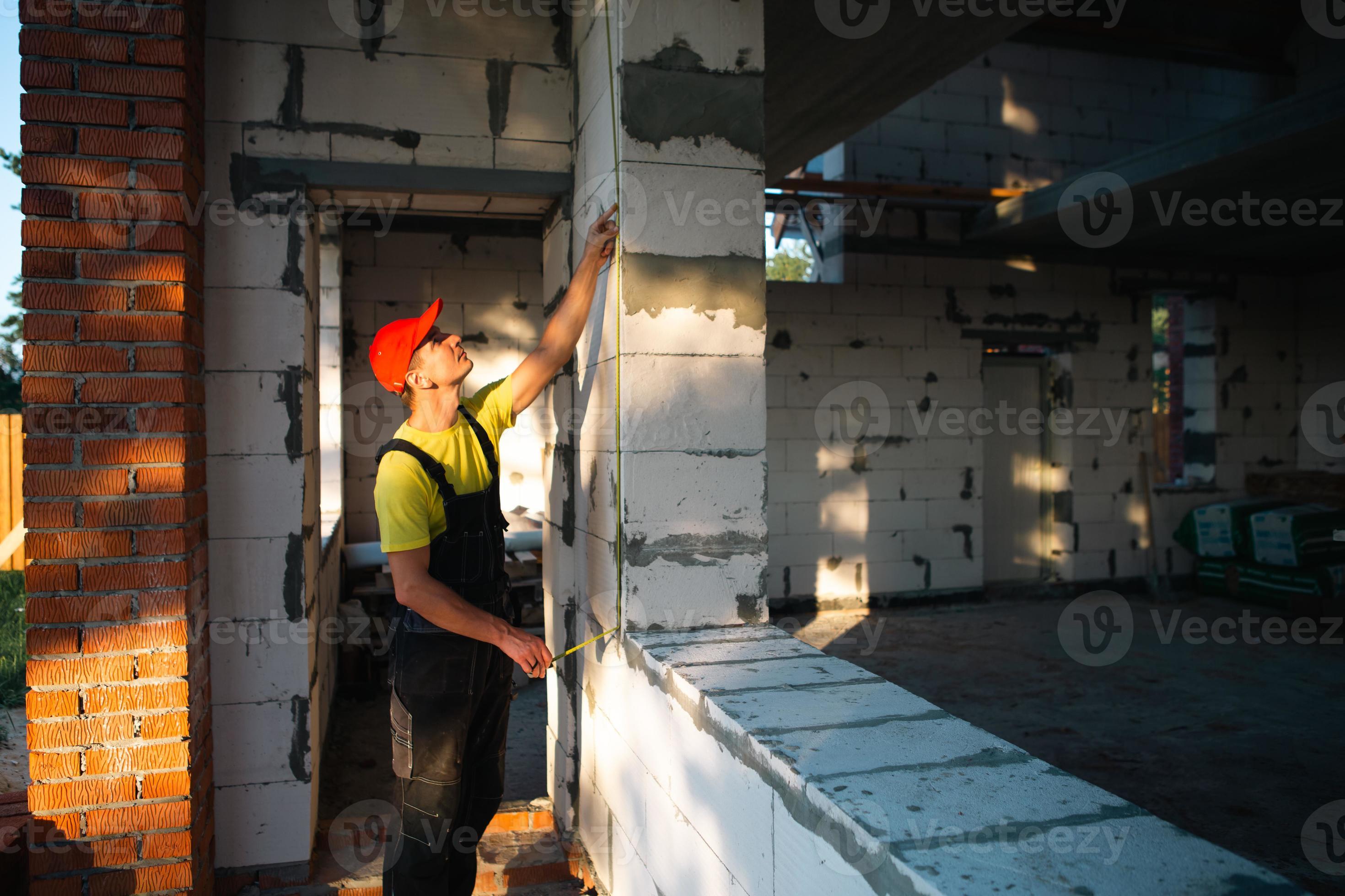 un ouvrier du bâtiment sur le chantier mesure la longueur de l